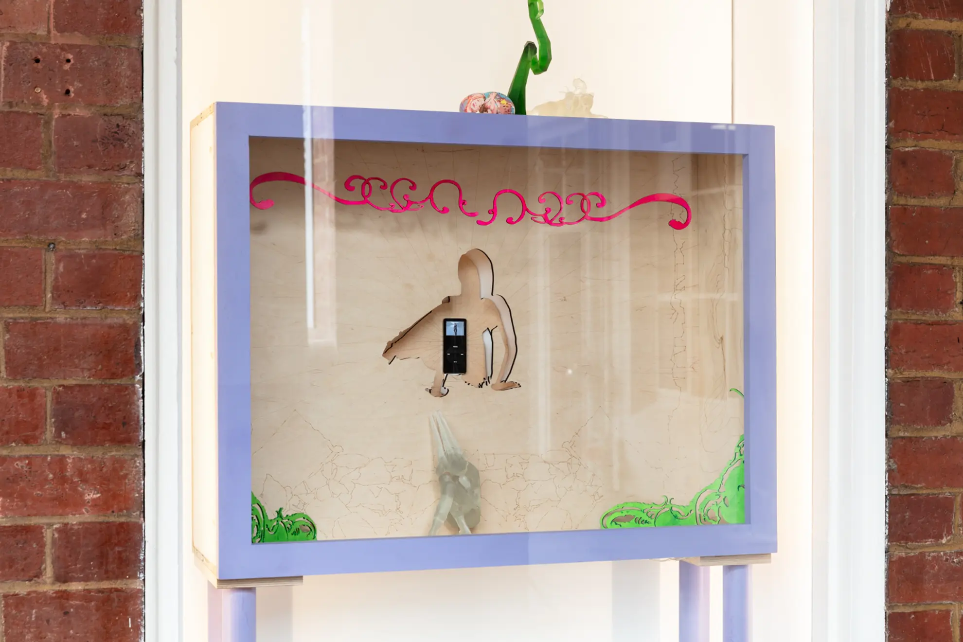 Installation view of the West Space window showing a wooden box containing a mixed media sculptural work.