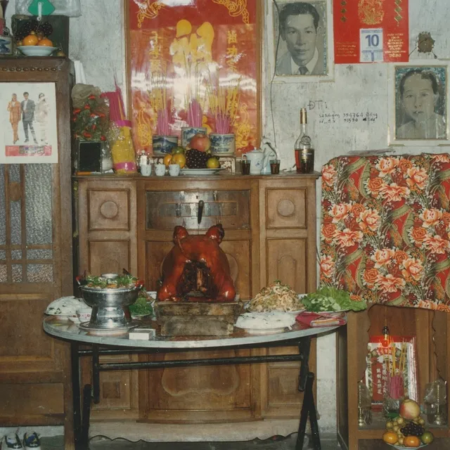 A living room with pictures on the walls, two wooden cabinets, a glass table and antique decor.
