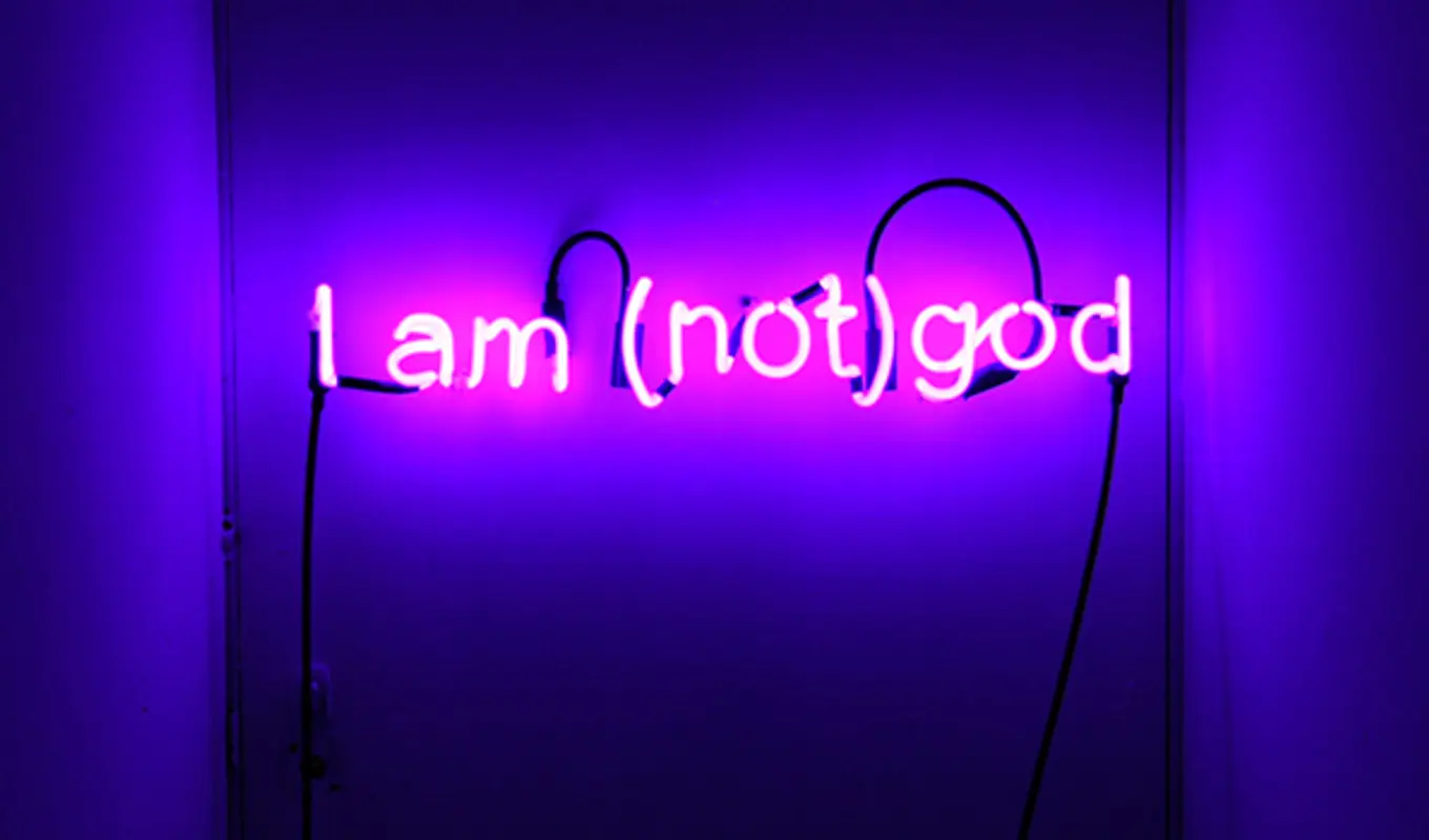 Purple led light sign reading 'I am (not) god'.