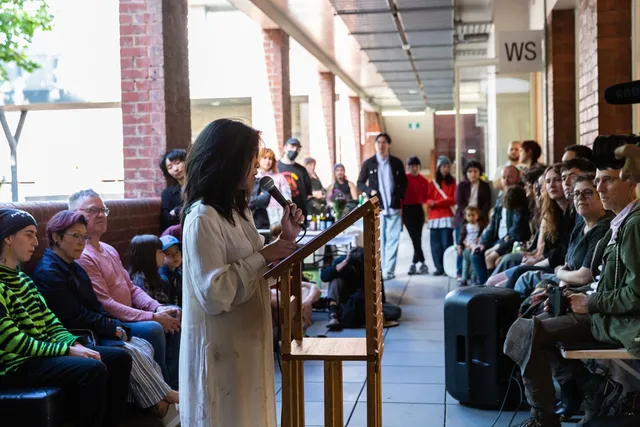 A person behind the podium speaking with the microphone to the crowd in the hallway.