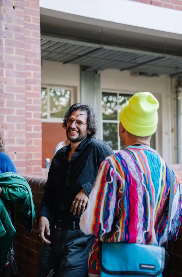 A person wearing glasses smiling beside a person with yellow beanies.