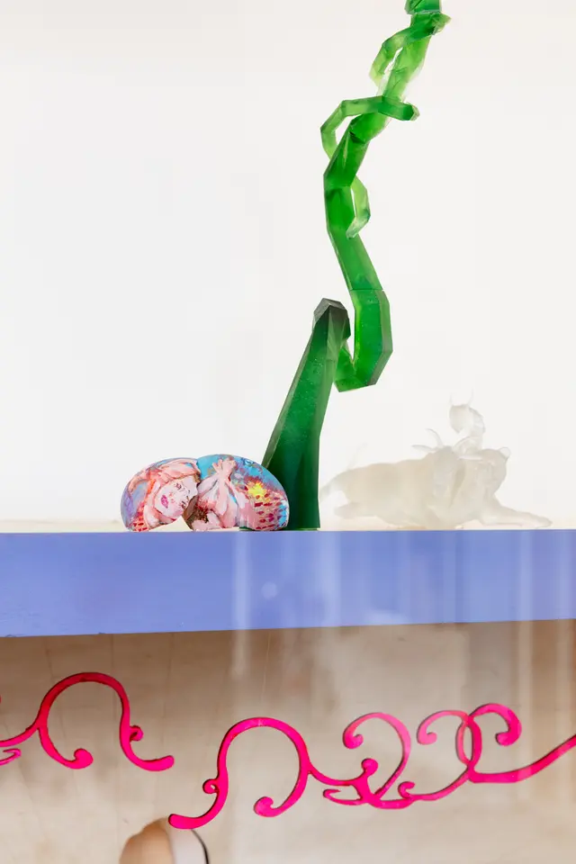 Close-up of Yanti Pengs 'Self-made: Invisible Architecture' which features neon green and pink swirly sculptural elements and a cracked eggshell with a figure painted on top.