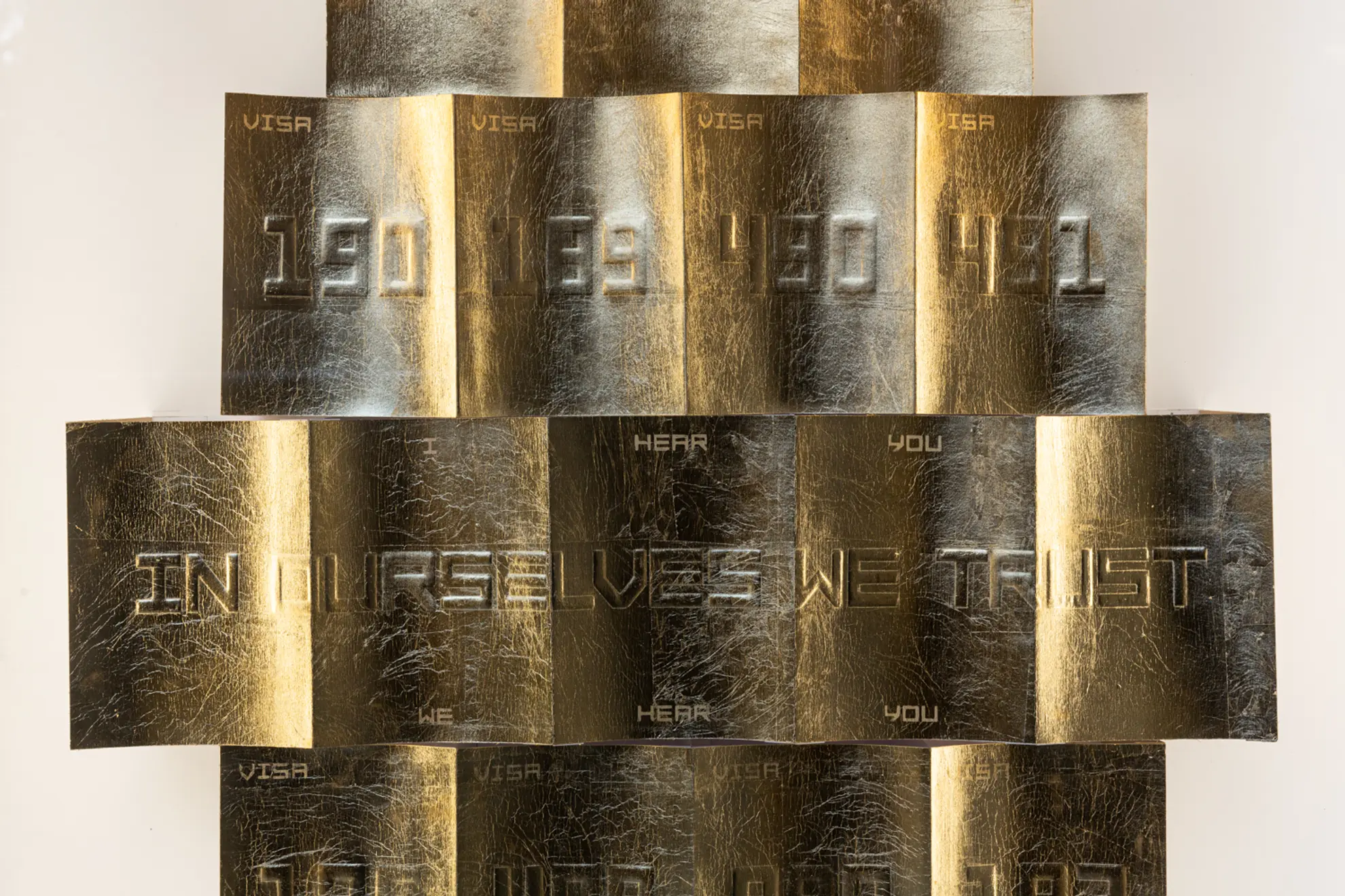 A close up detail on Thang Do's artwork of gold embossed visa codes. Visible text within the artwork reads "I hear you. We hear you" and "In ourselves we trust"