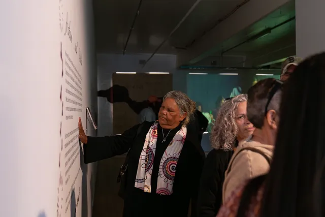 A person reading the text on the wall with one hand touching the wall.