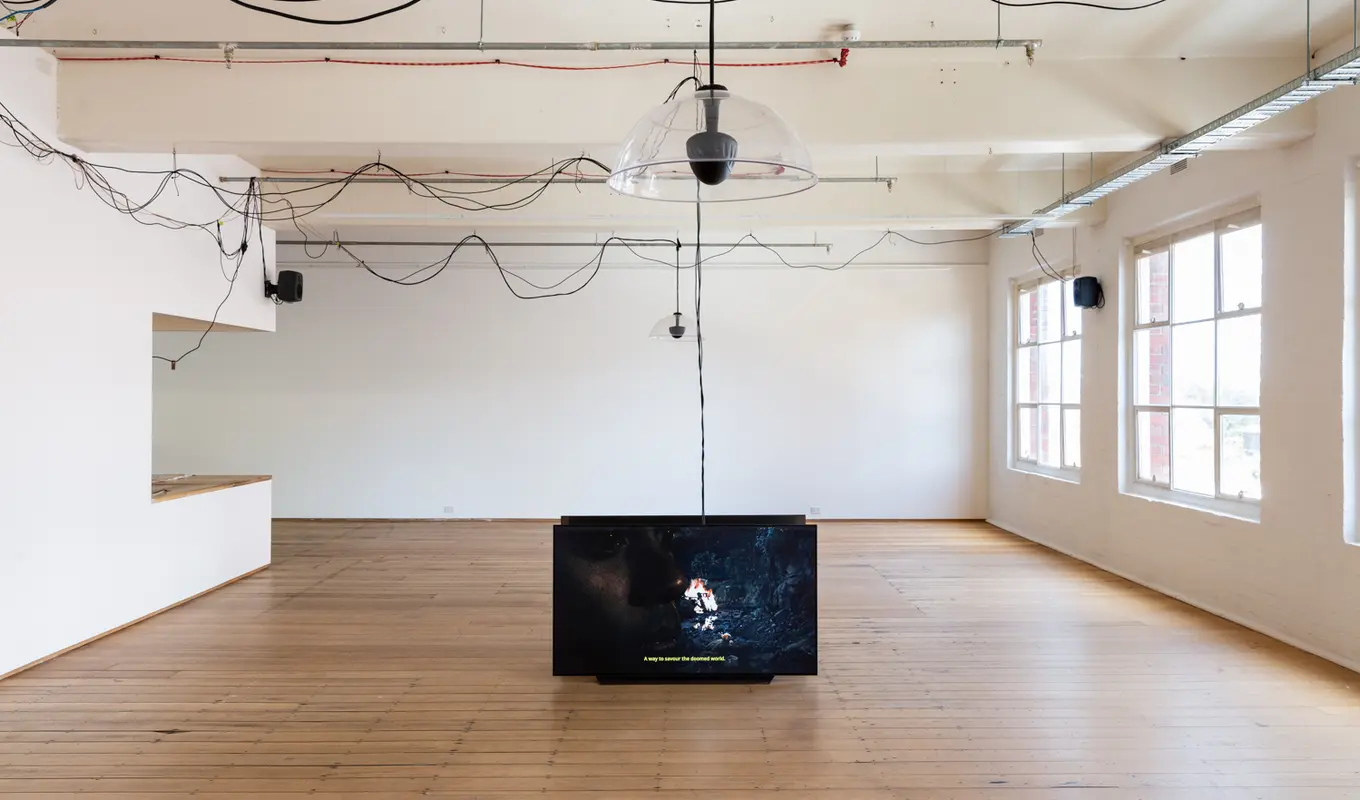 2 large screens stand on the floor of West Space Gallery. There are black cords that drape across the roof and all around the space.