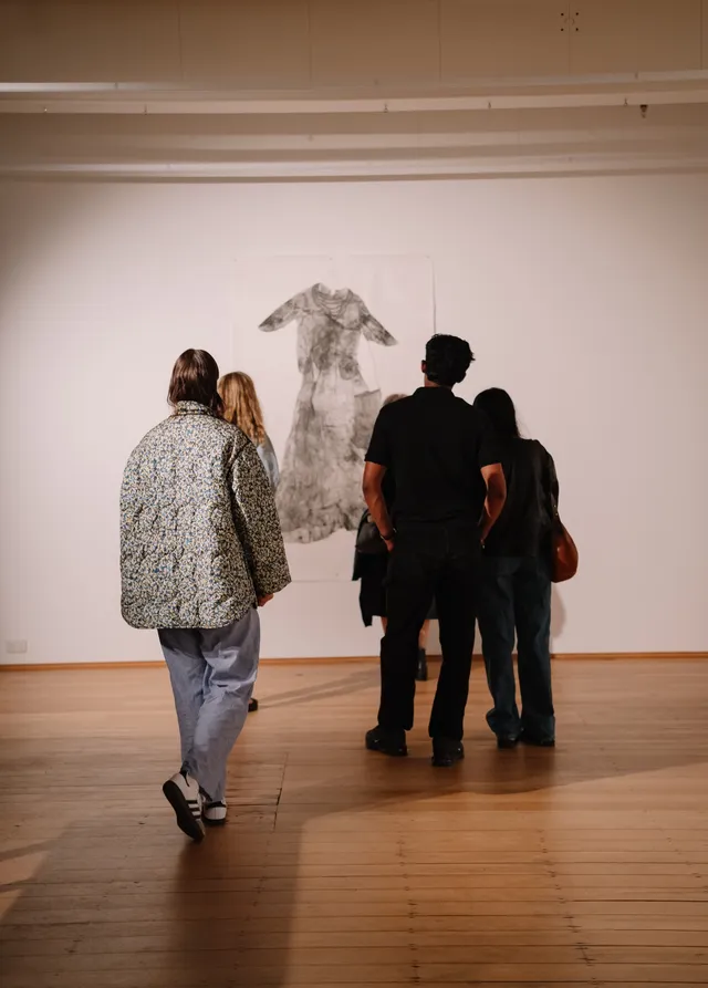 The back of people looking at an art piece hanging on the wall.