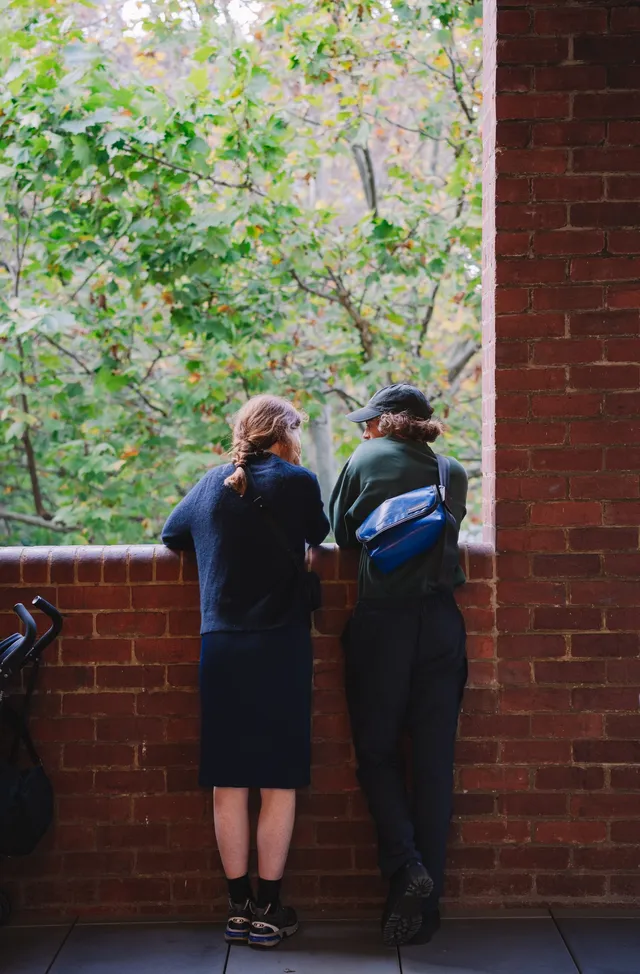 Two people standing in front of the brick balcony.