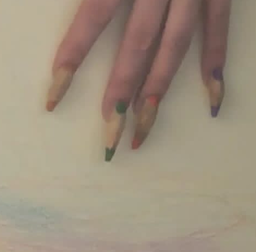 A detail shot of four fingers with long ballerina shaped acrylic nails. The nails are painted a beige tone with two coloured dots on each end of the nail.