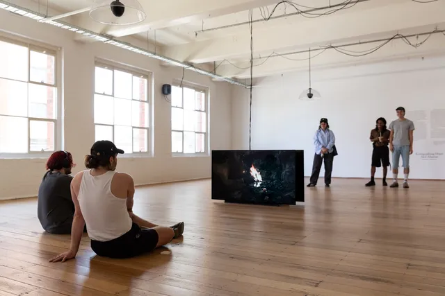 People sitting and standing watching videos from the screens from two sides.