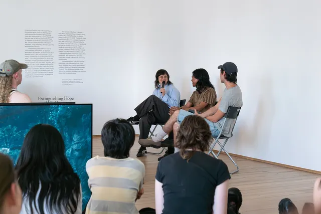 An audience sits facing a panel of three people in conversation.