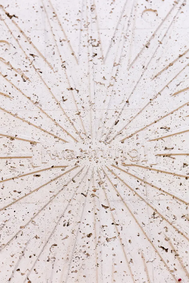 a close up detail picture of a concrete cast object that resembles a man hole cover. There is a word visible that says "warming".