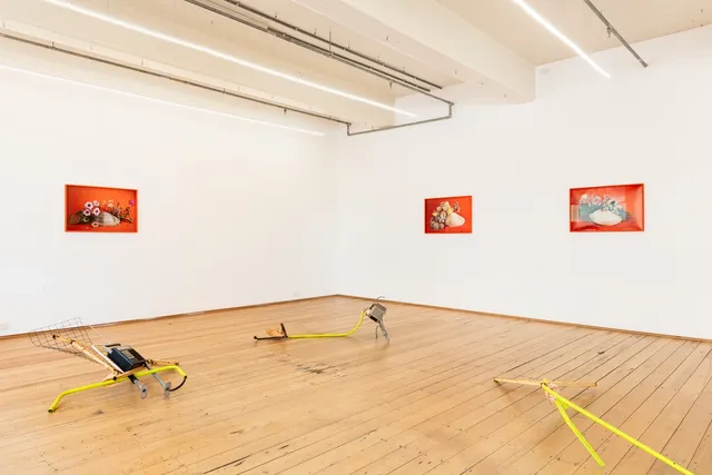 Corner of the gallery install, showing three framed pieces hanging on the wall and three sculptural installation pieces comprised of metal segments.