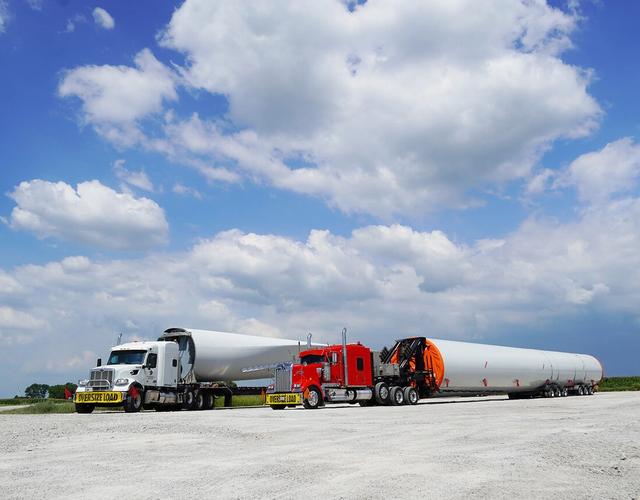Two semi trucks side by side that say oversized load on the front bumper