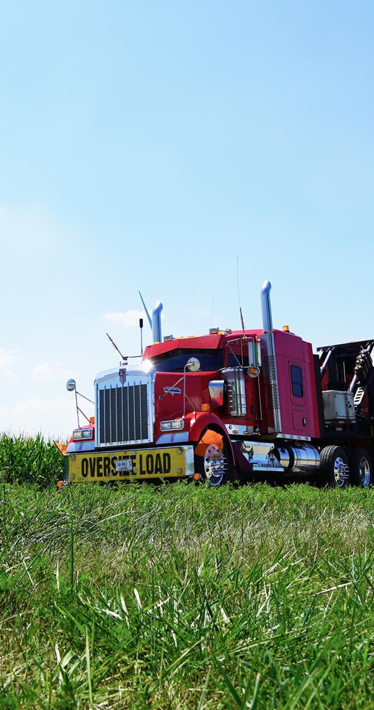 Large semi-truck driving past a cornfield
