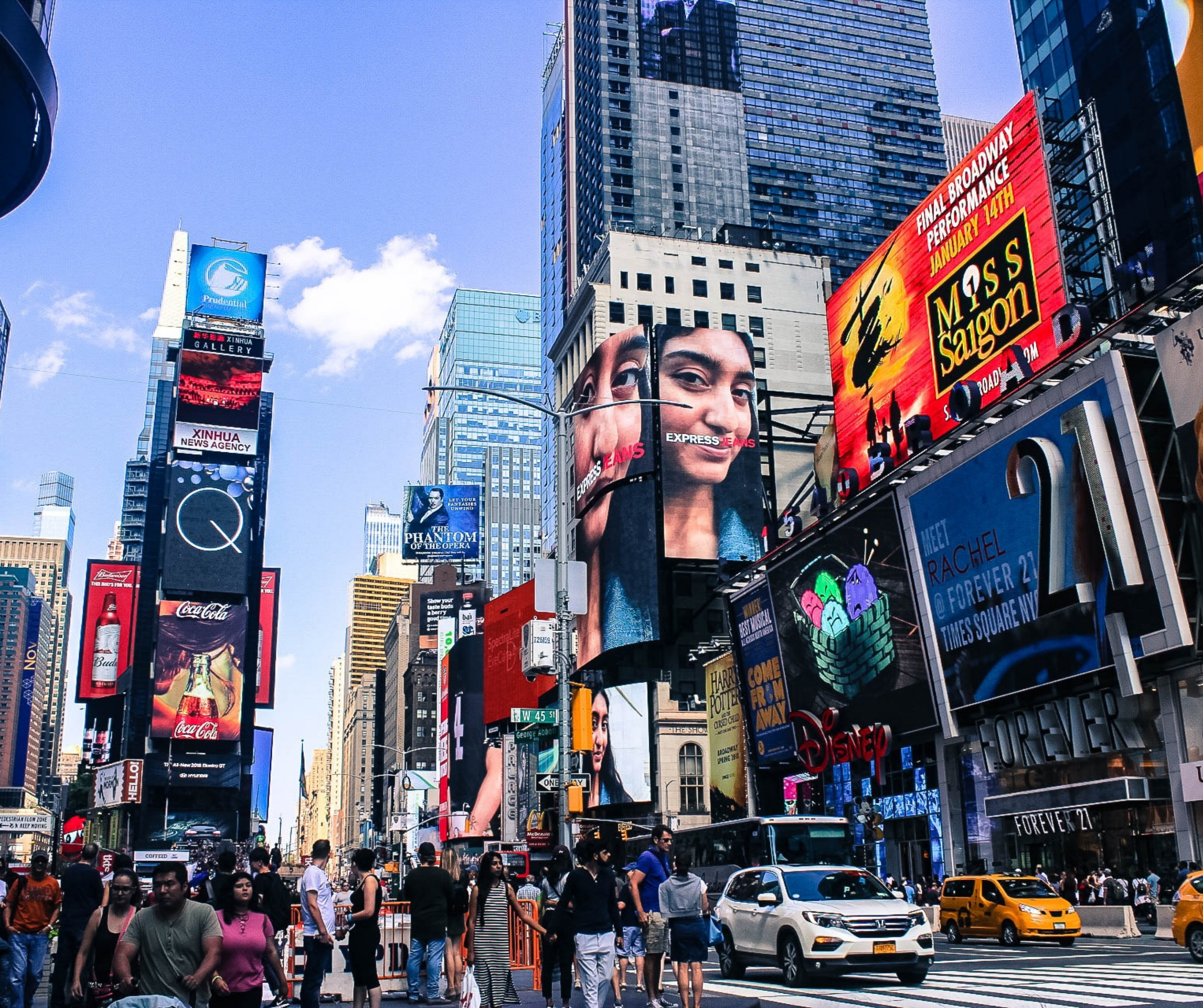 Times Square in New York City, featuring numerous bright billboards and crowds of people walking on the streets