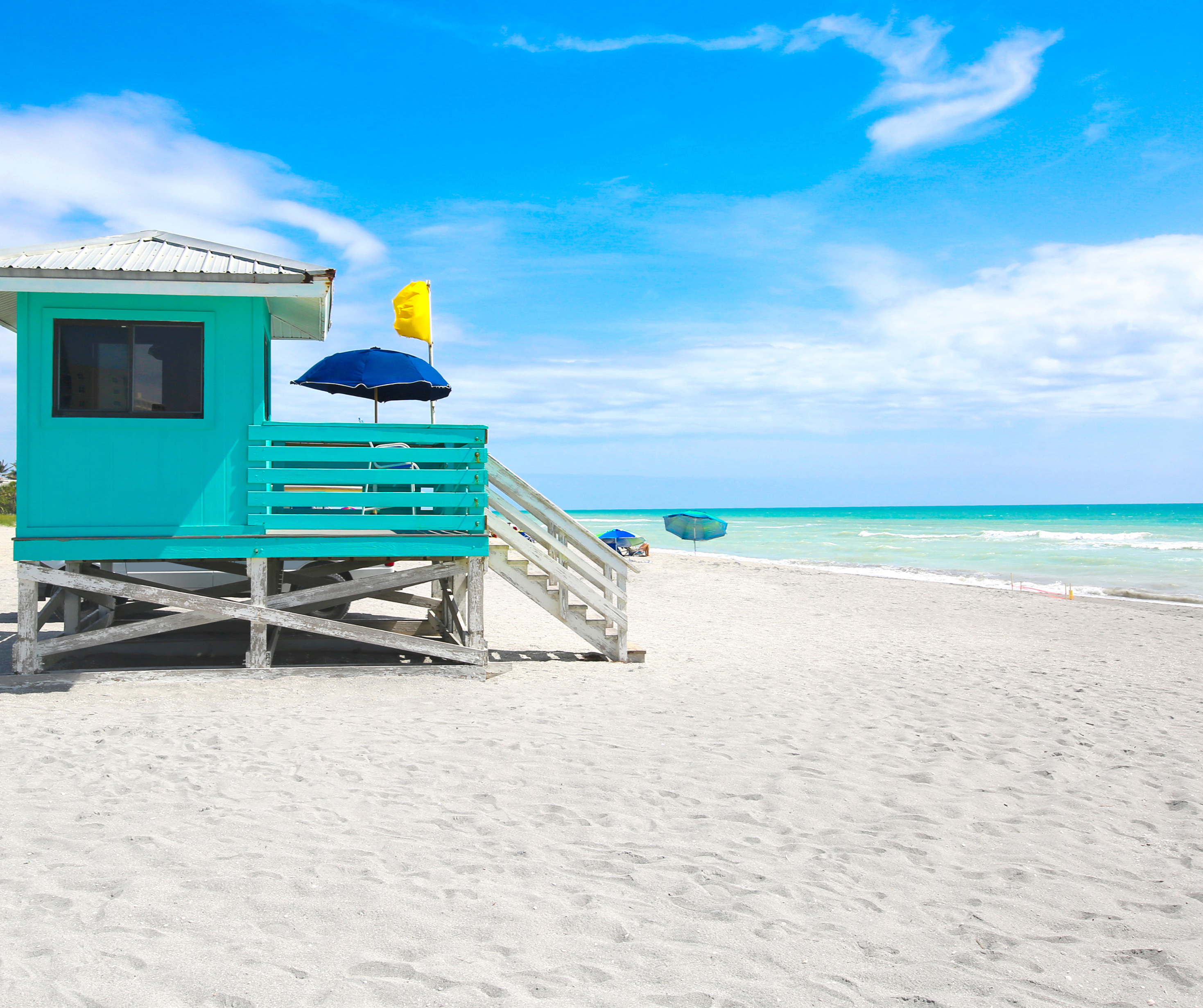 A small wooden cabin located near the ocean with a clear blue sky and the sea in the background.