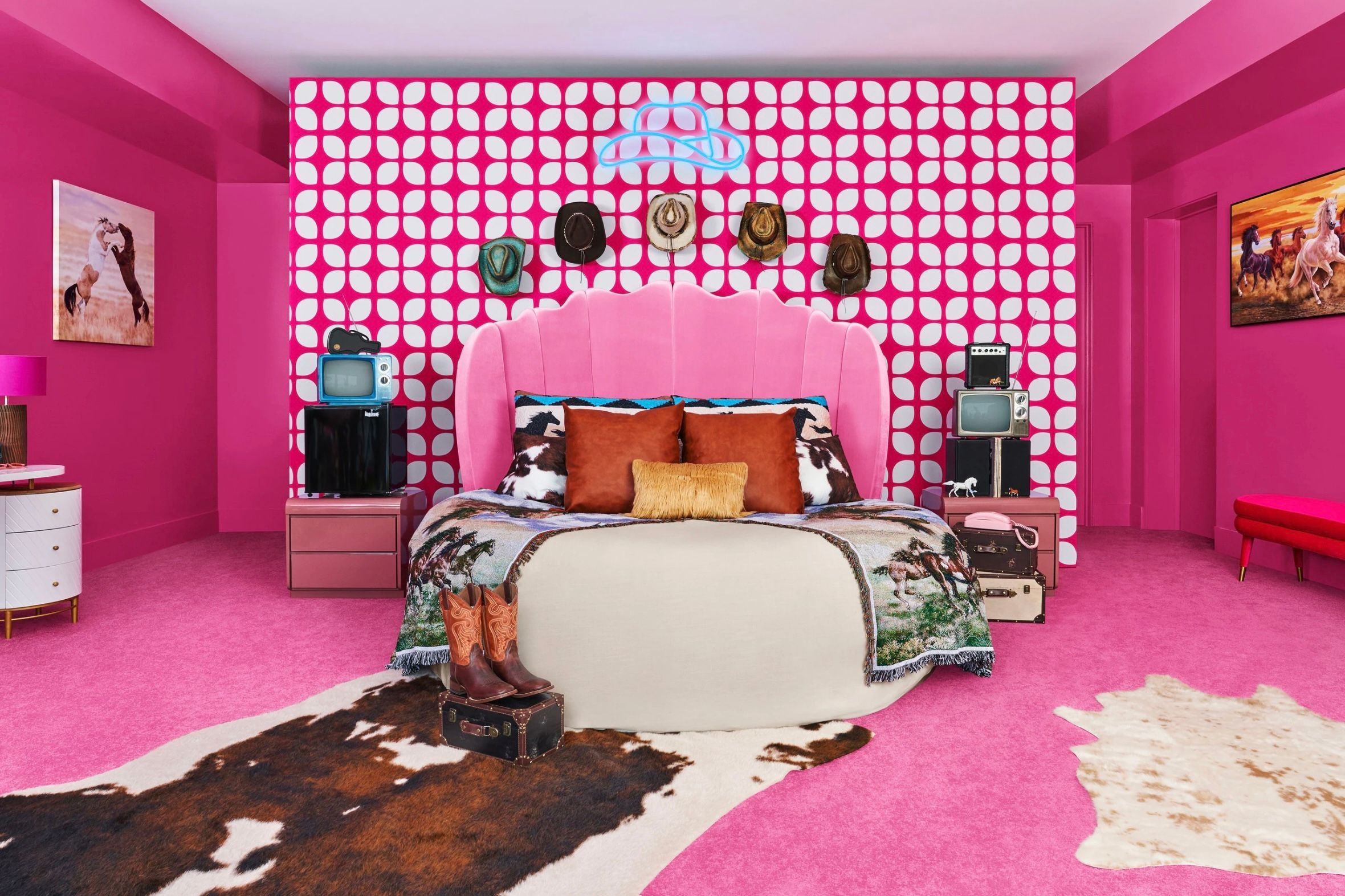 A pink-themed bedroom in the Malibu Barbie Dreamhouse with a pink headboard, patterned wall, and cowboy hats.