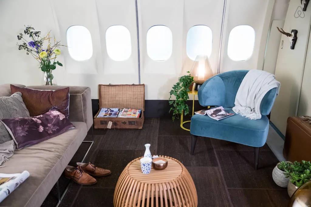 Interior view of the lounge area inside an airplane converted into a lodging option, with seating and decorative elements.