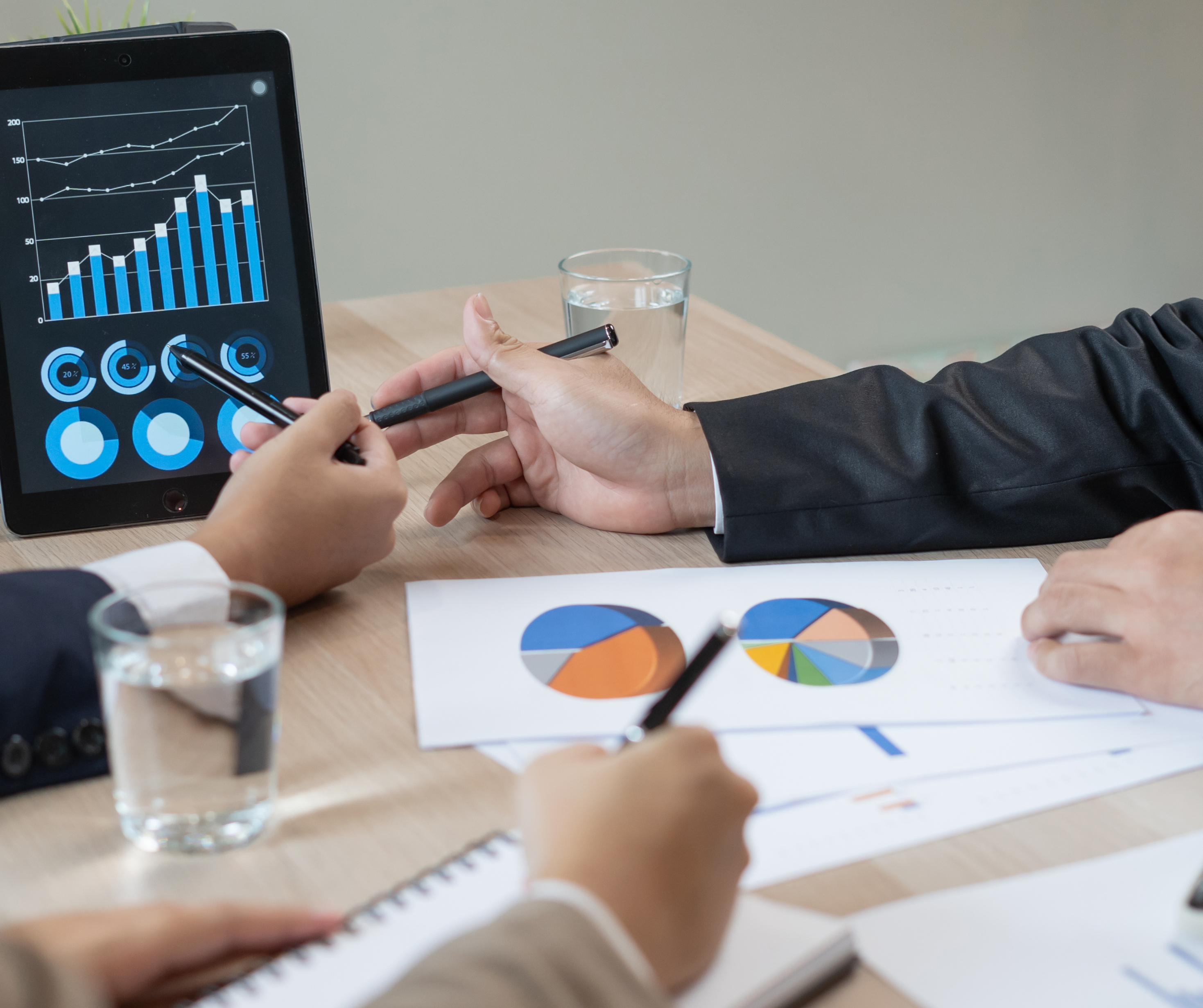  Business professionals analyzing sales data and graphs on a tablet.