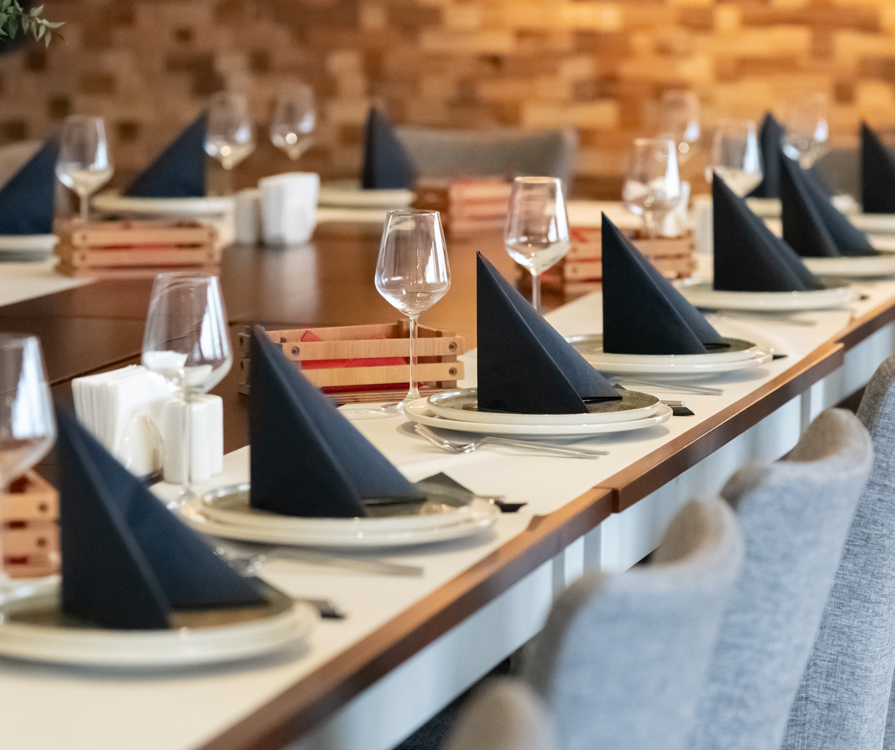 A close-up view of an elegantly arranged table with black napkins folded into triangles, wine glasses, and plates, prepared for a formal event.