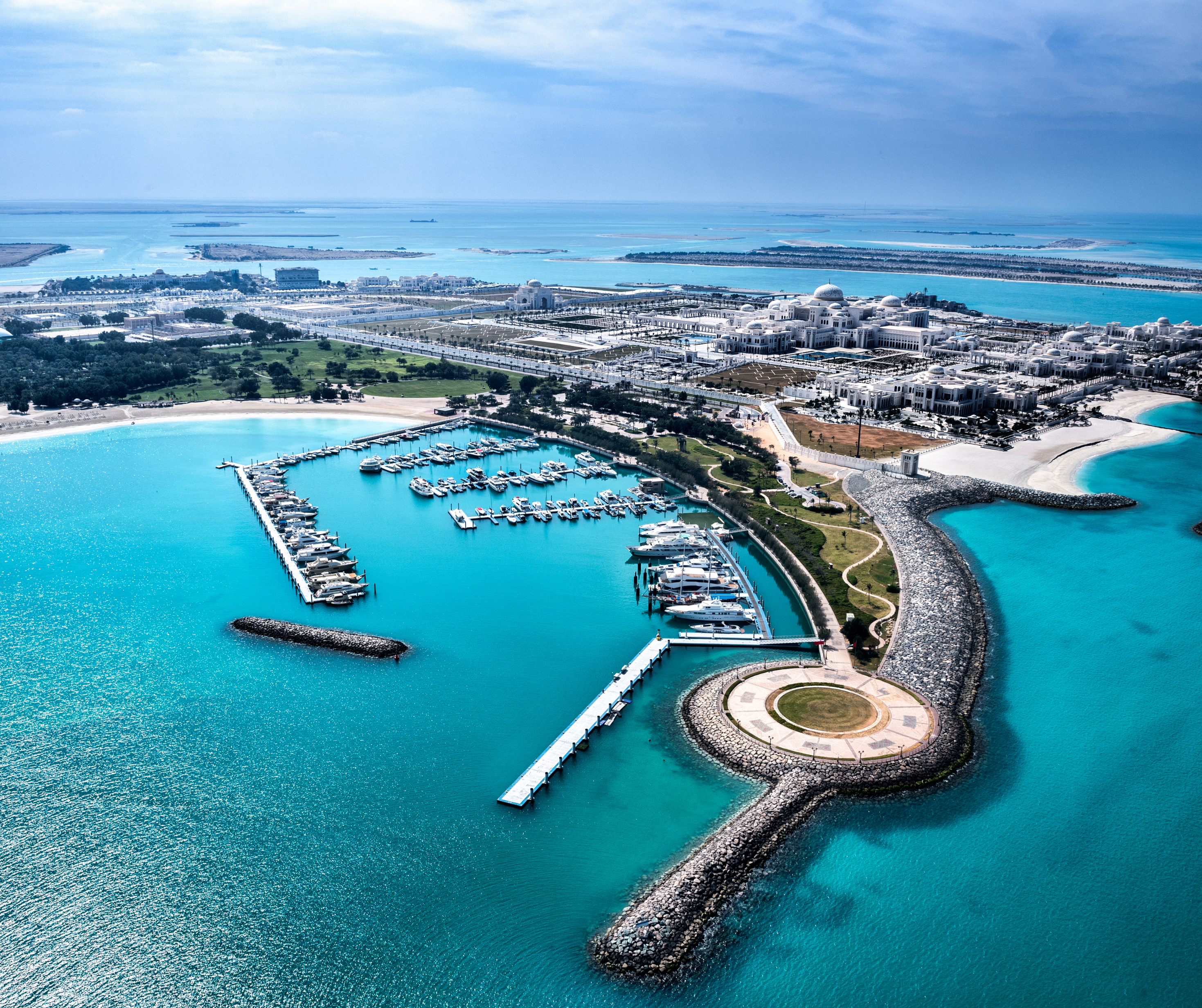 Aerial view of the coastline and marina in Abu Dhabi, showcasing turquoise waters and modern architecture.