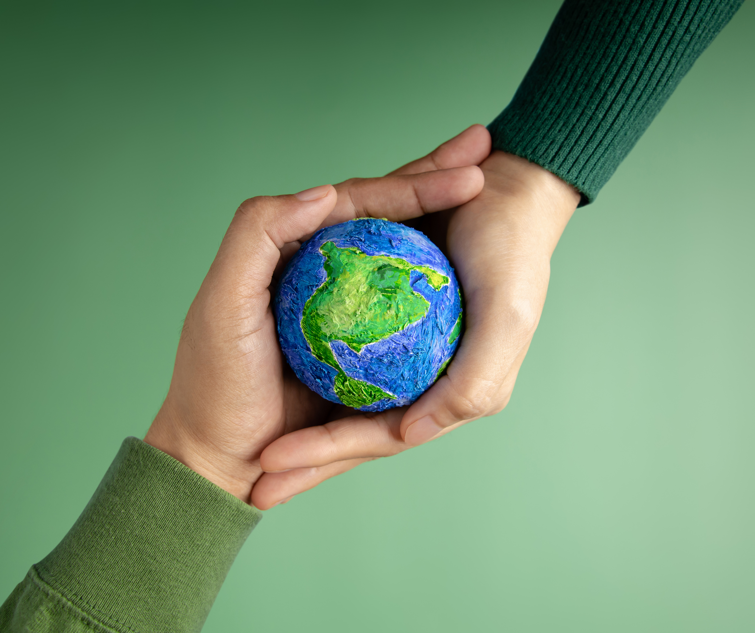 Two hands holding a small model of the Earth, representing environmental conservation and sustainability.