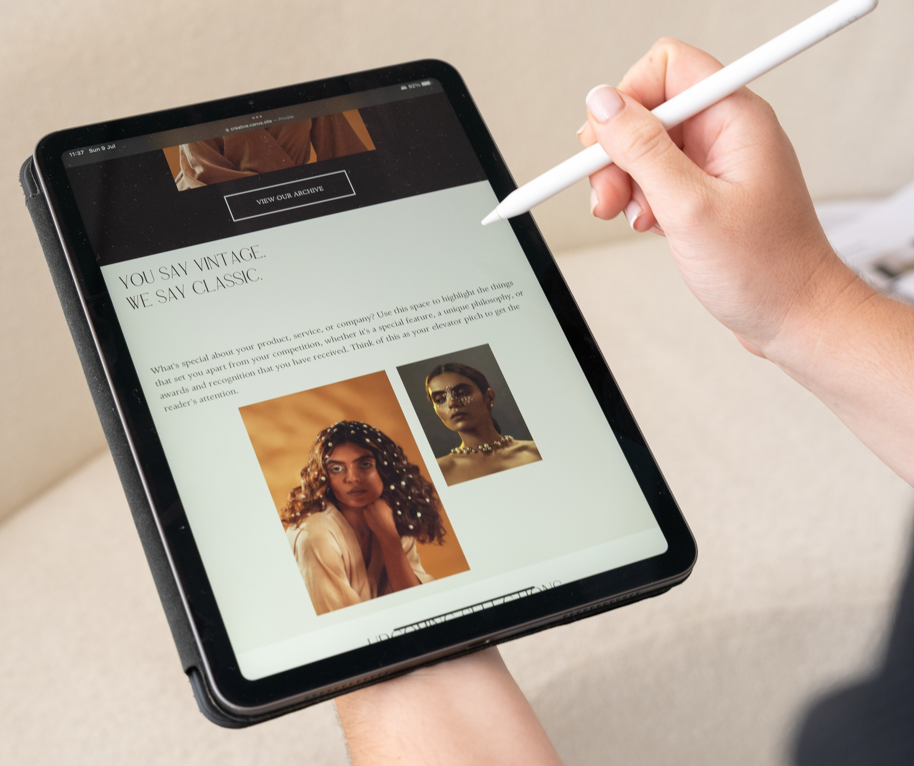 A person using a stylus to interact with a tablet displaying a website with a classic and vintage design theme