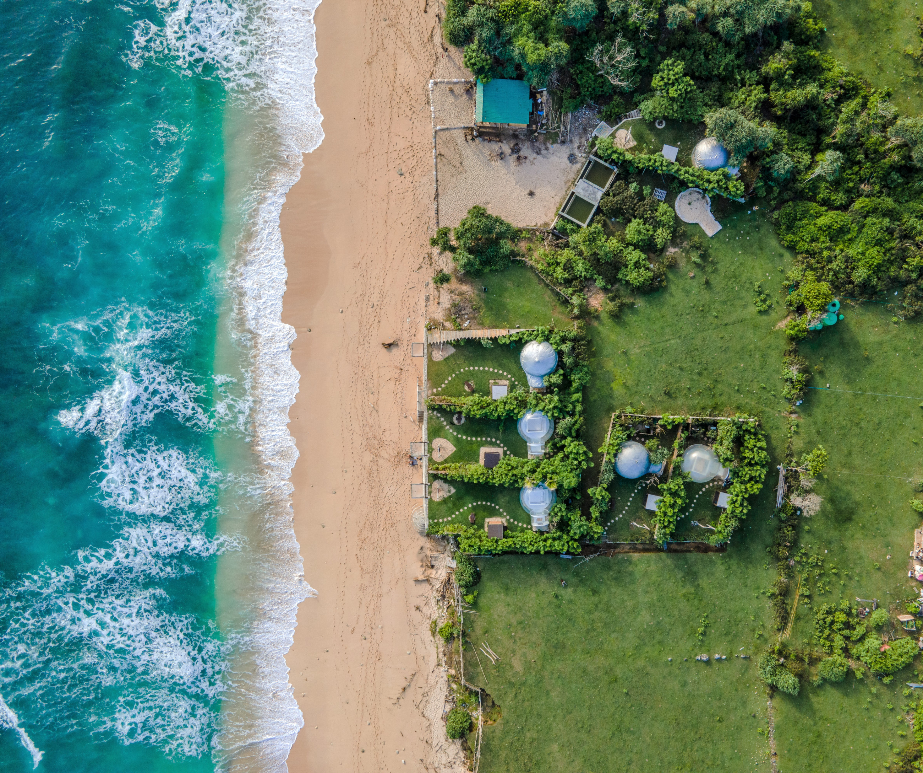 Aerial view of a beachside eco-resort with domes and greenery