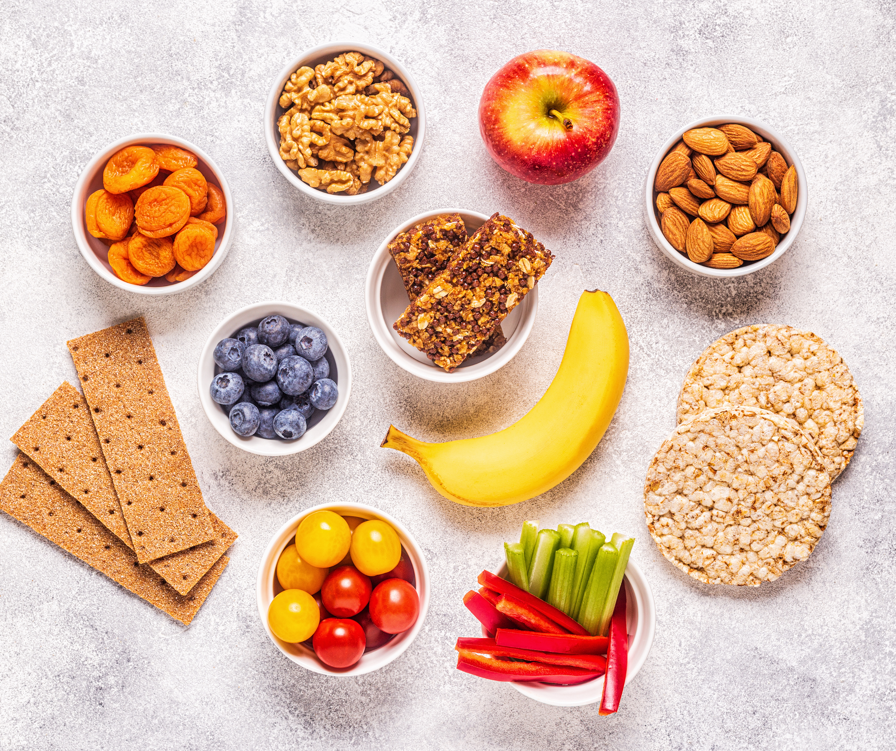 An assortment of healthy snacks including fruits, vegetables, and nuts arranged on a table, ideal for kids' school lunches.