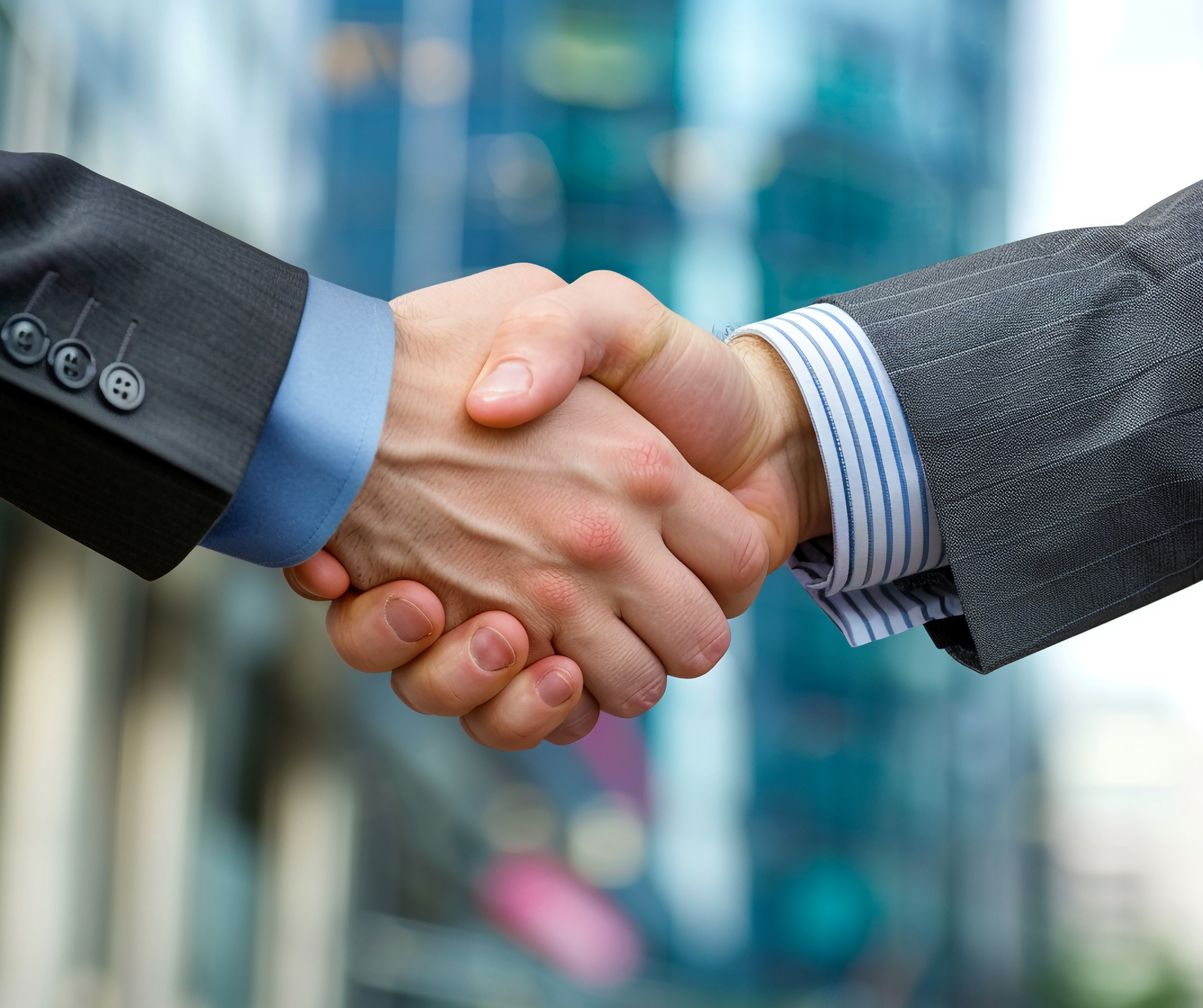 Close-up of two businessmen in suits shaking hands, indicating a successful business deal or partnership.