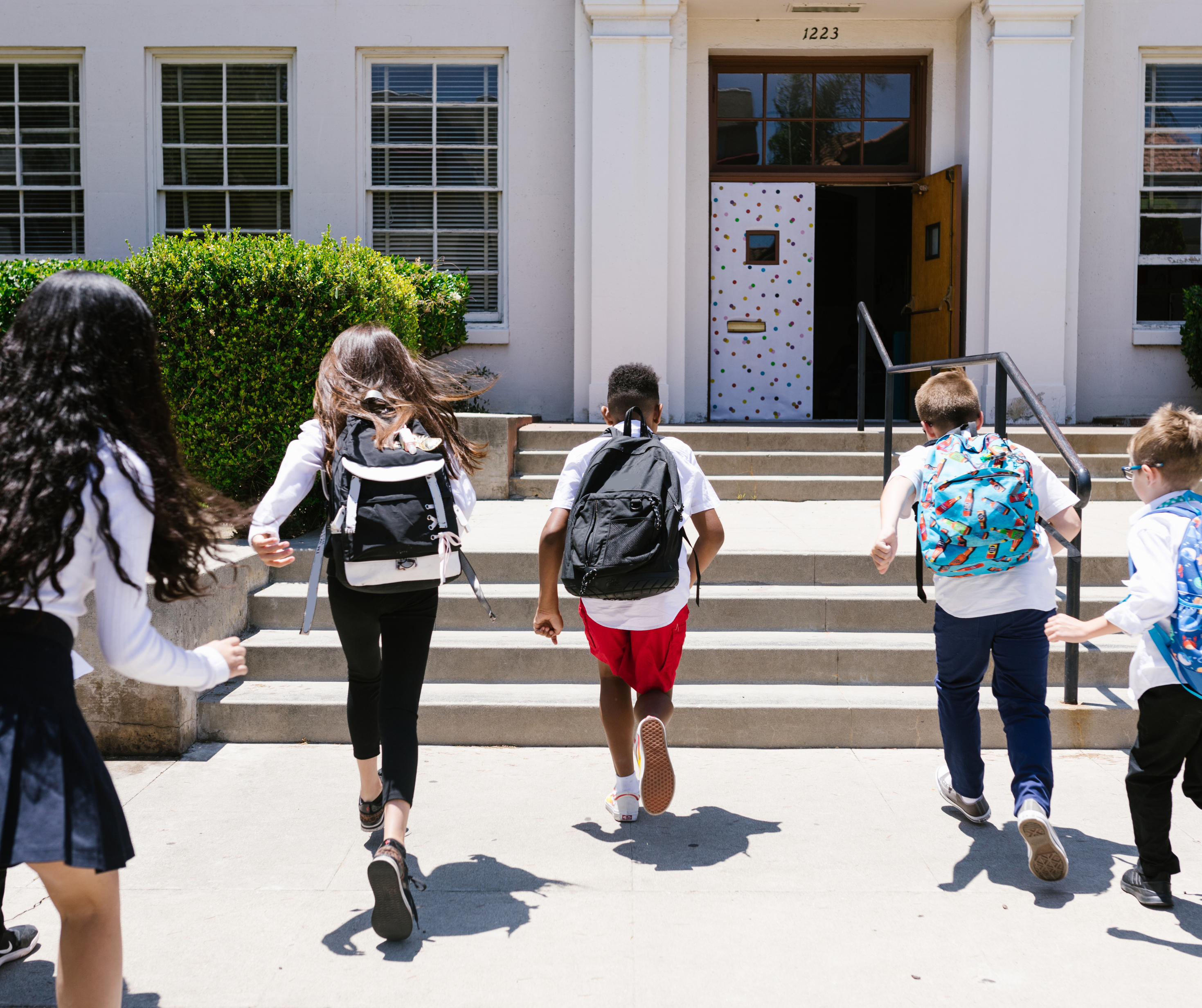 A group of children with backpacks walking happily to school along the sidewalk