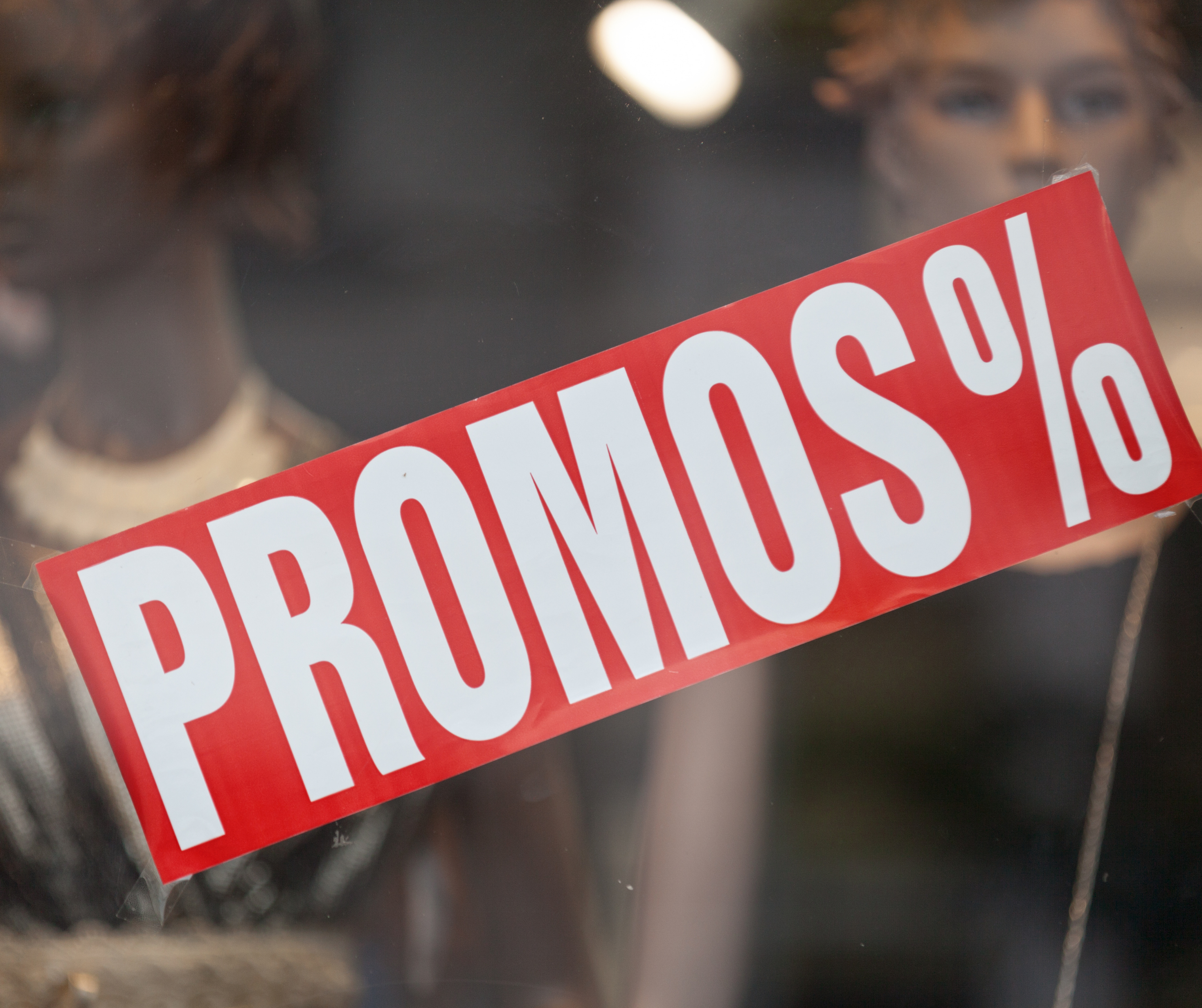 A red sign with the word 'PROMOS' displayed in a store window, indicating sales and discounts during the holiday shopping season.