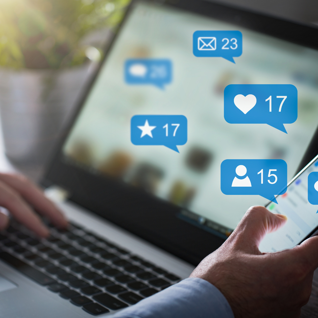 Shows social media engagement icons like messages, likes, and followers floating above a laptop screen, illustrating online interaction and metrics
