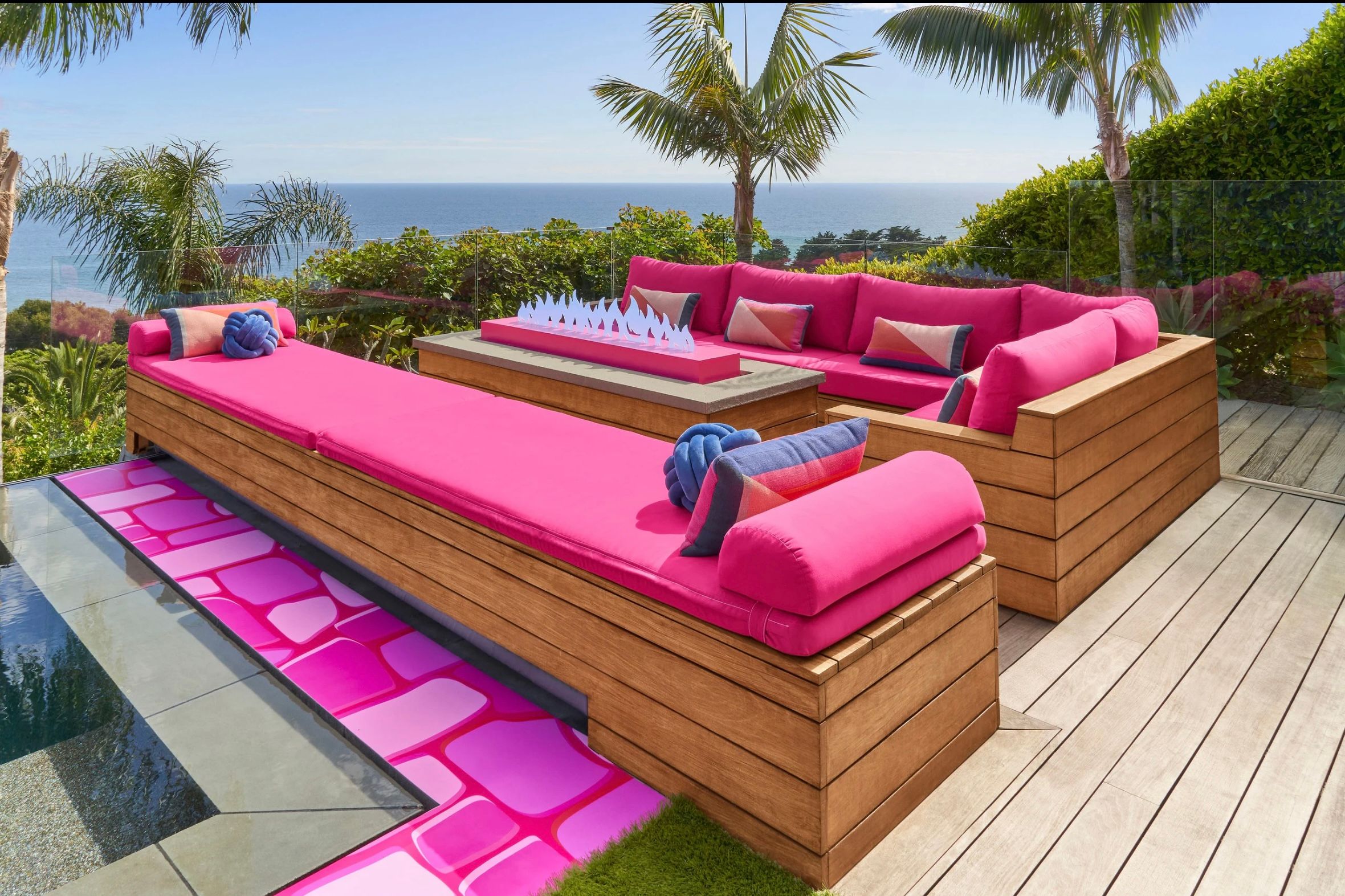 Outdoor lounge area with pink cushioned seating and ocean view at the Malibu Barbie Dreamhouse.