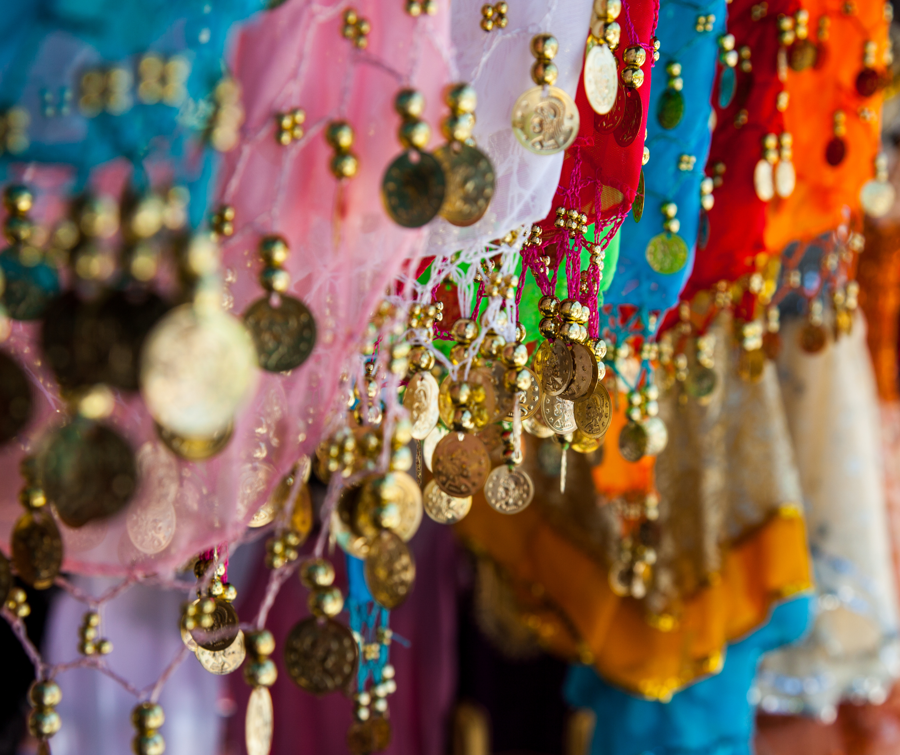 Close-up of colorful traditional souvenir scarves with gold coins in Abu Dhabi.