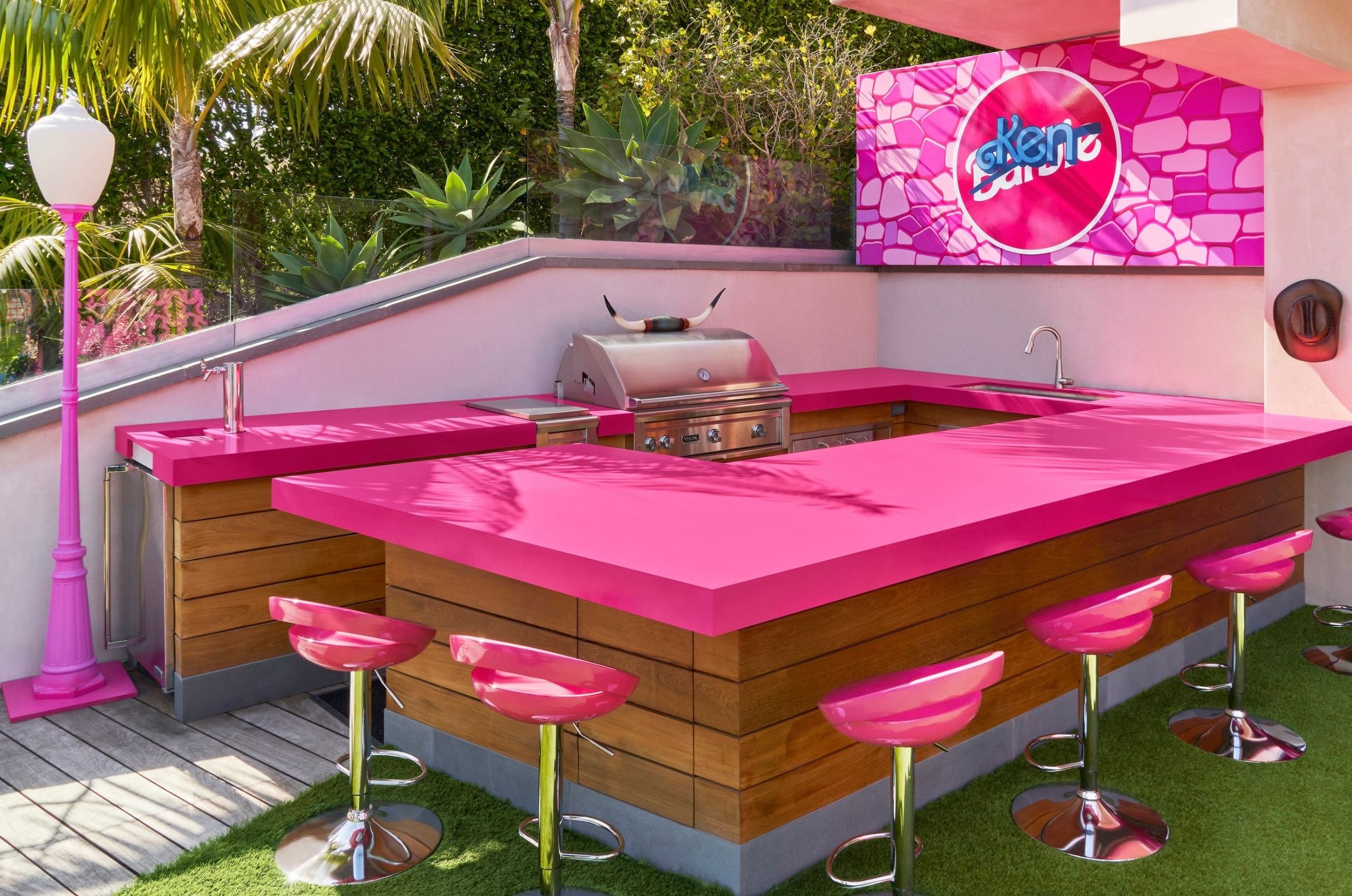 Outdoor kitchen with pink countertops and bar stools in the Malibu Barbie Dreamhouse.