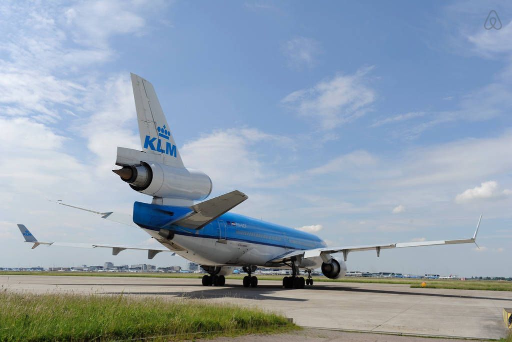 Exterior of a stationary KLM airplane on a runway, converted into a unique lodging option on Airbnb.