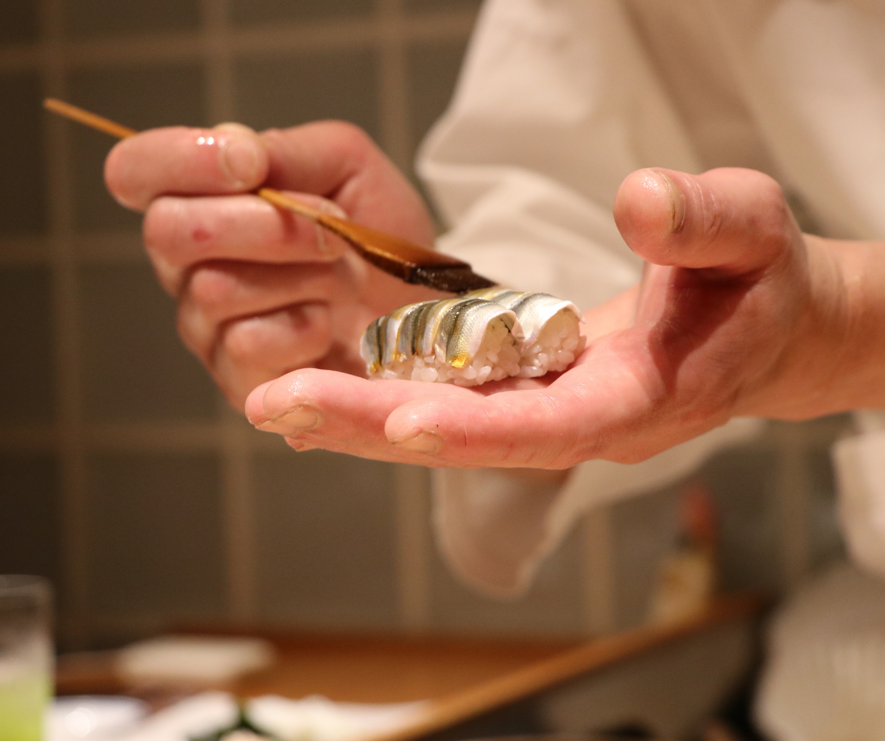 Close-up of a chef's hands carefully preparing sushi, highlighting the delicate work involved in creating the dish.