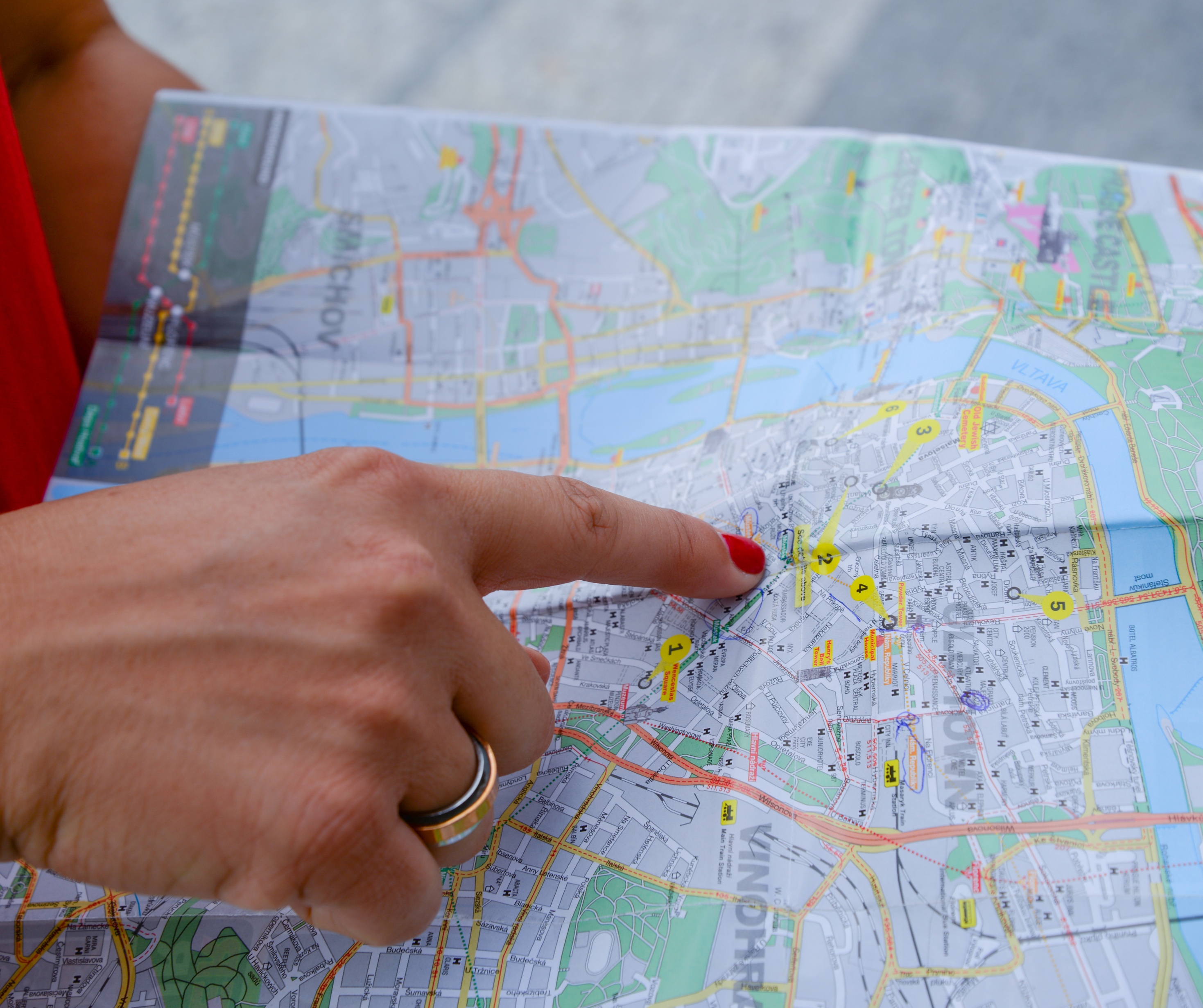 A person pointing to a specific spot on a map, surrounded by various markers and location icons, indicating the importance of choosing the right location for an event or business.