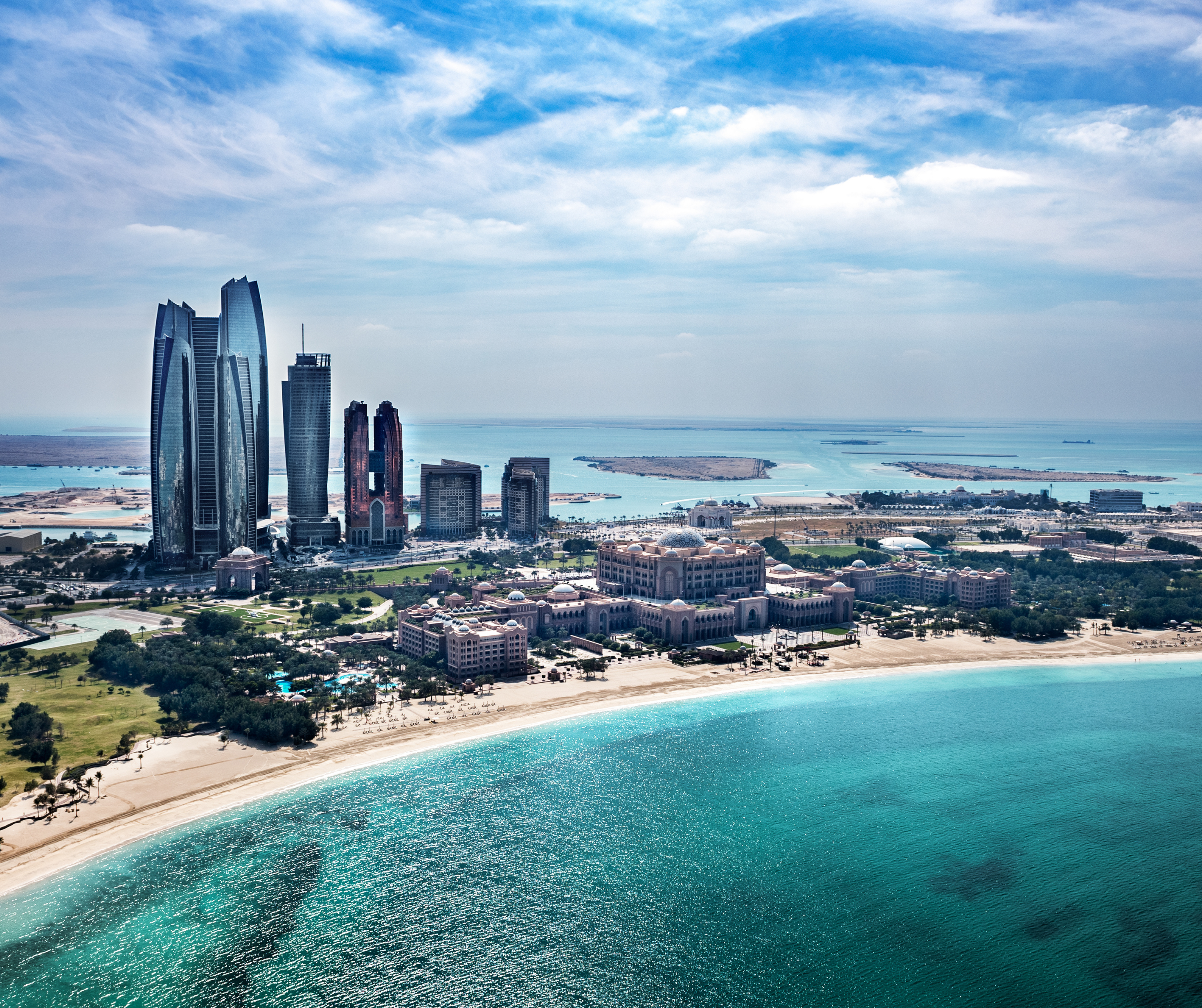 Aerial view of Abu Dhabi's beach skyline with Etihad Towers and Emirates Palace.