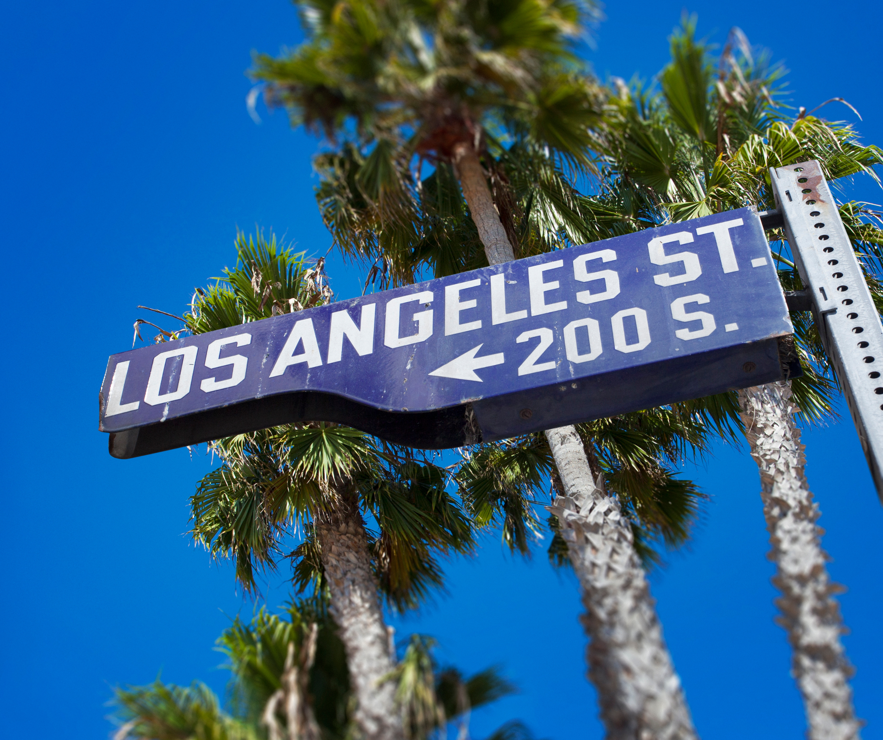 A green highway road sign pointing towards Los Angeles with distance information.