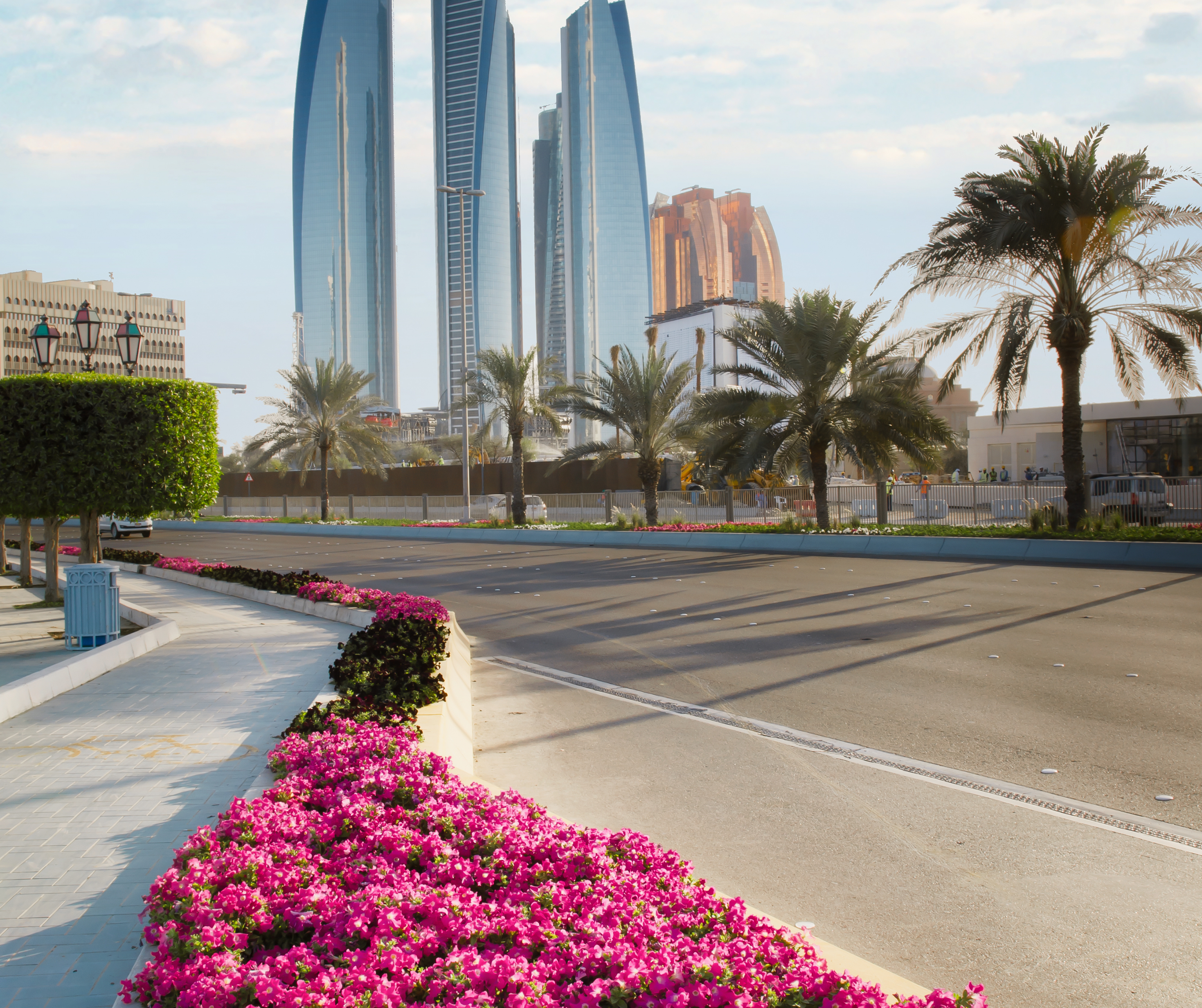  Landscaped street in Abu Dhabi with towering skyscrapers in the background.