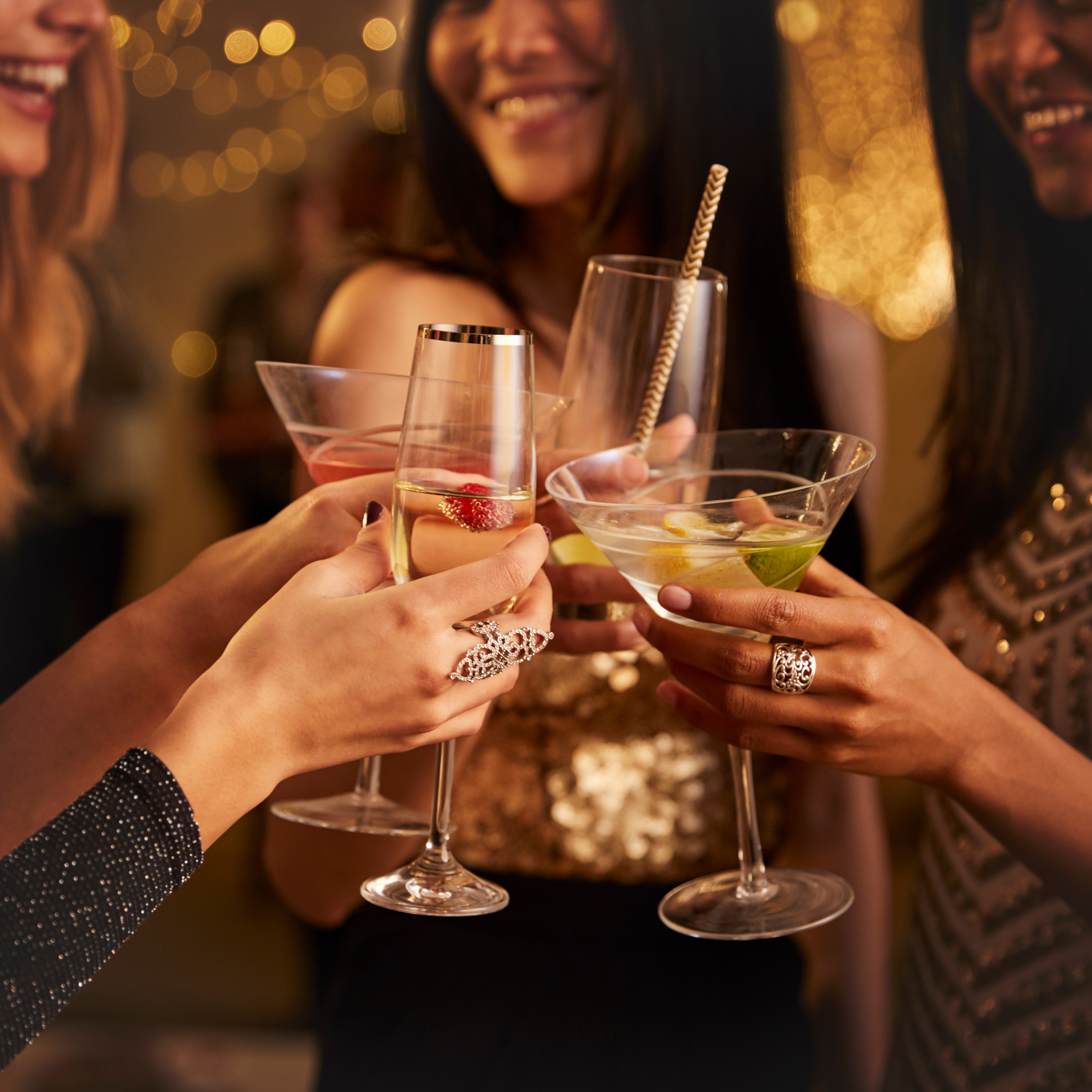 A group of friends toasting with various cocktails in an elegant party setting, highlighting their joyful expressions and stylish attire