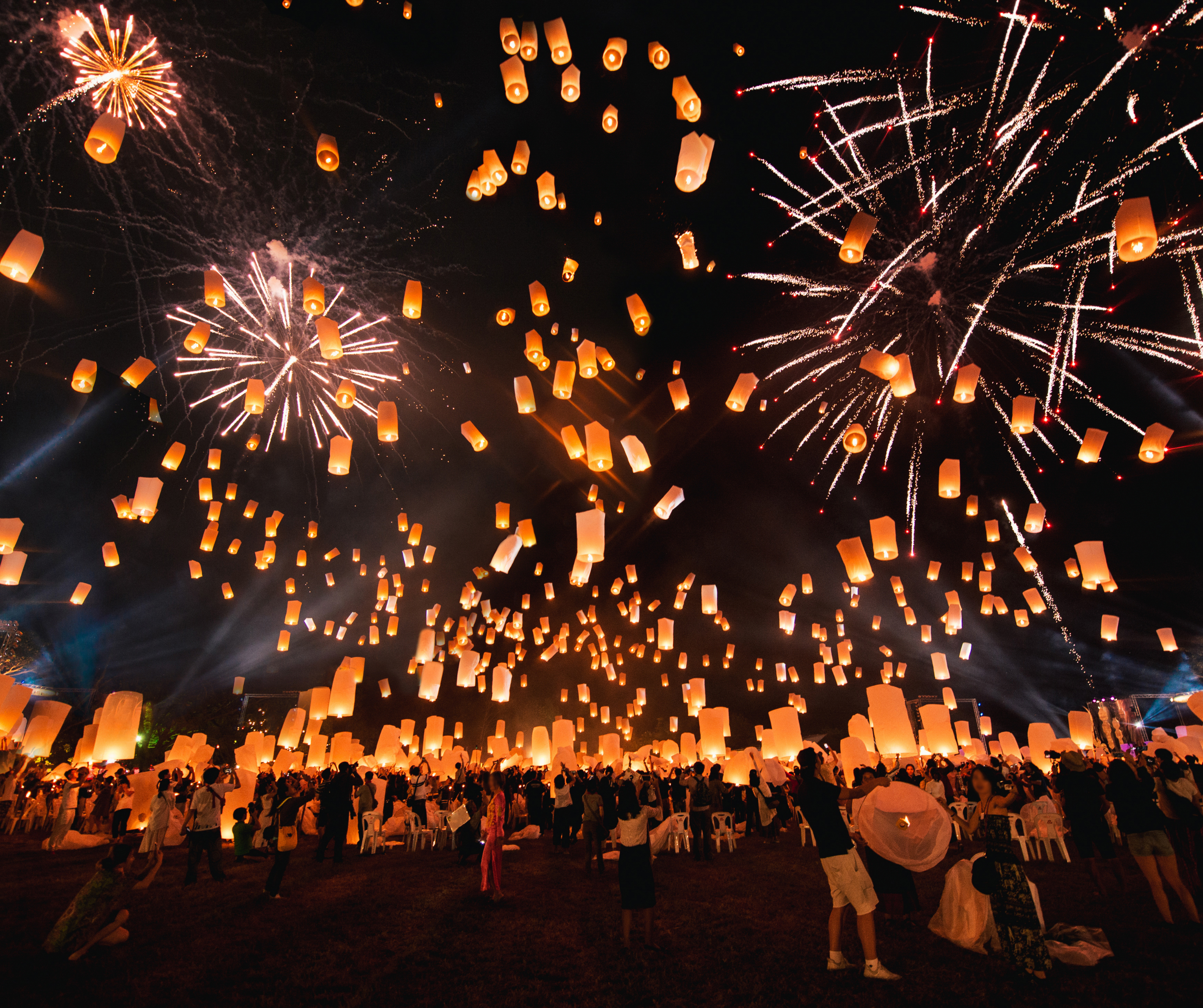 Numerous sky lanterns floating into the night sky during a lantern festival, creating a beautiful and serene scene with warm, glowing lights.