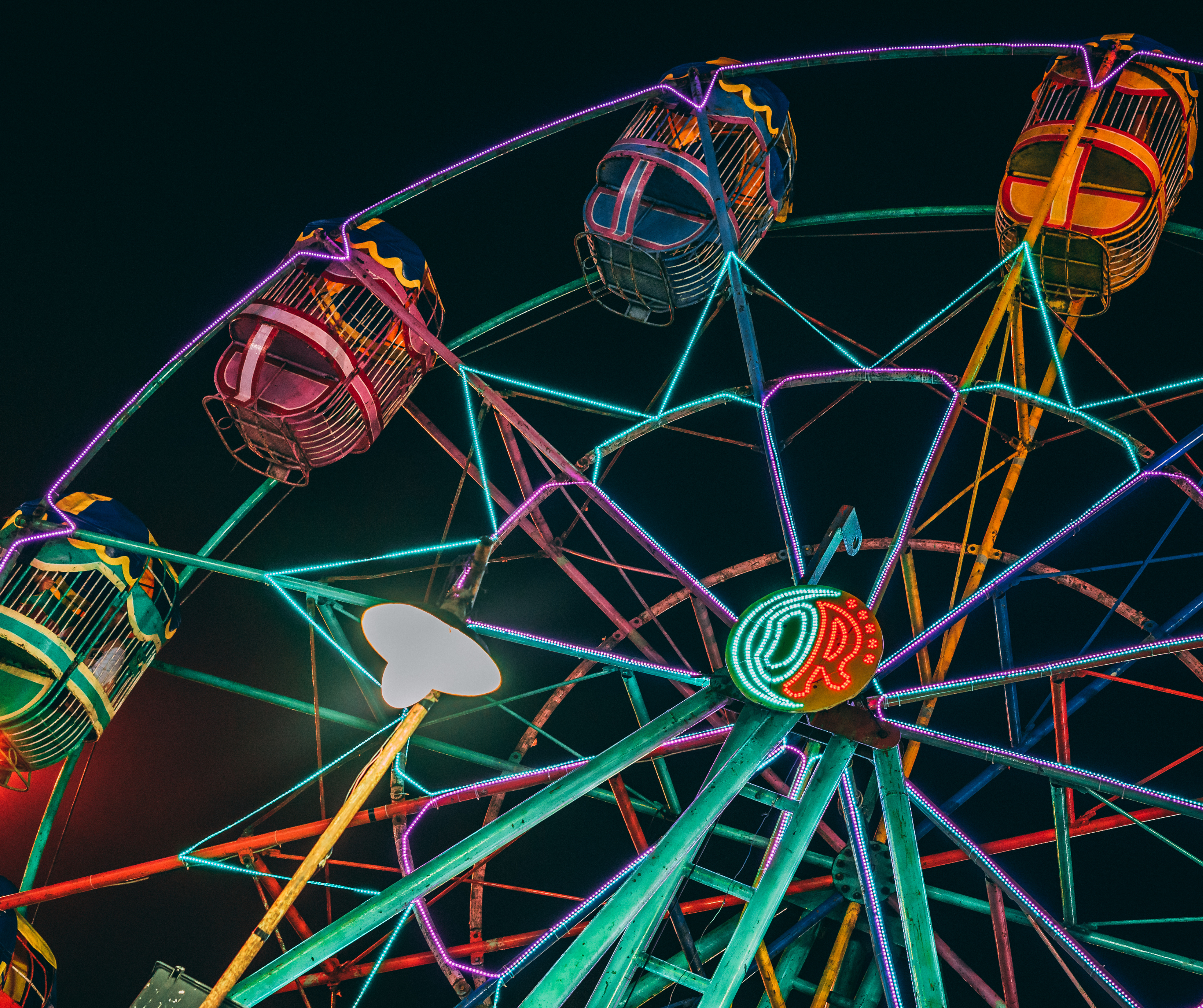 Vibrant Ferris wheel illuminated with colorful lights against a dark sky at a festival in Los Angeles.