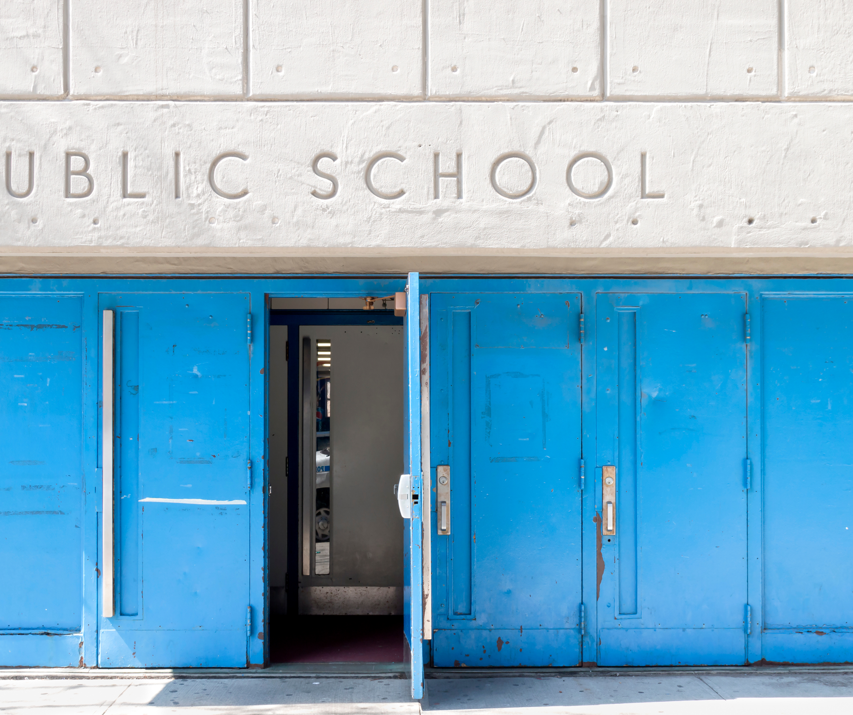 The main entrance of a school with large doors, welcoming signage, and well-maintained landscaping