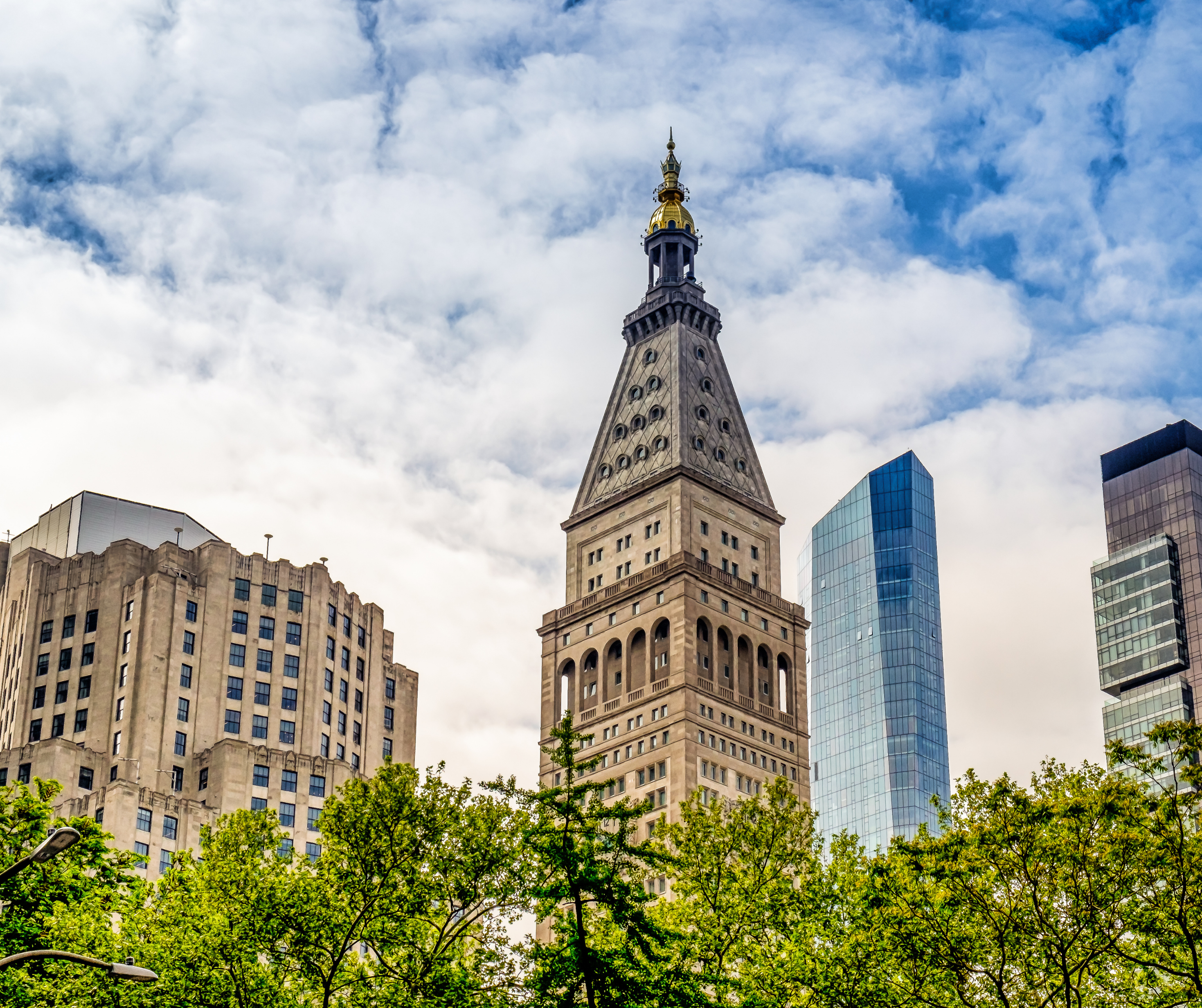 The iconic Met Life Tower in the Flatiron District with surrounding buildings and green trees.