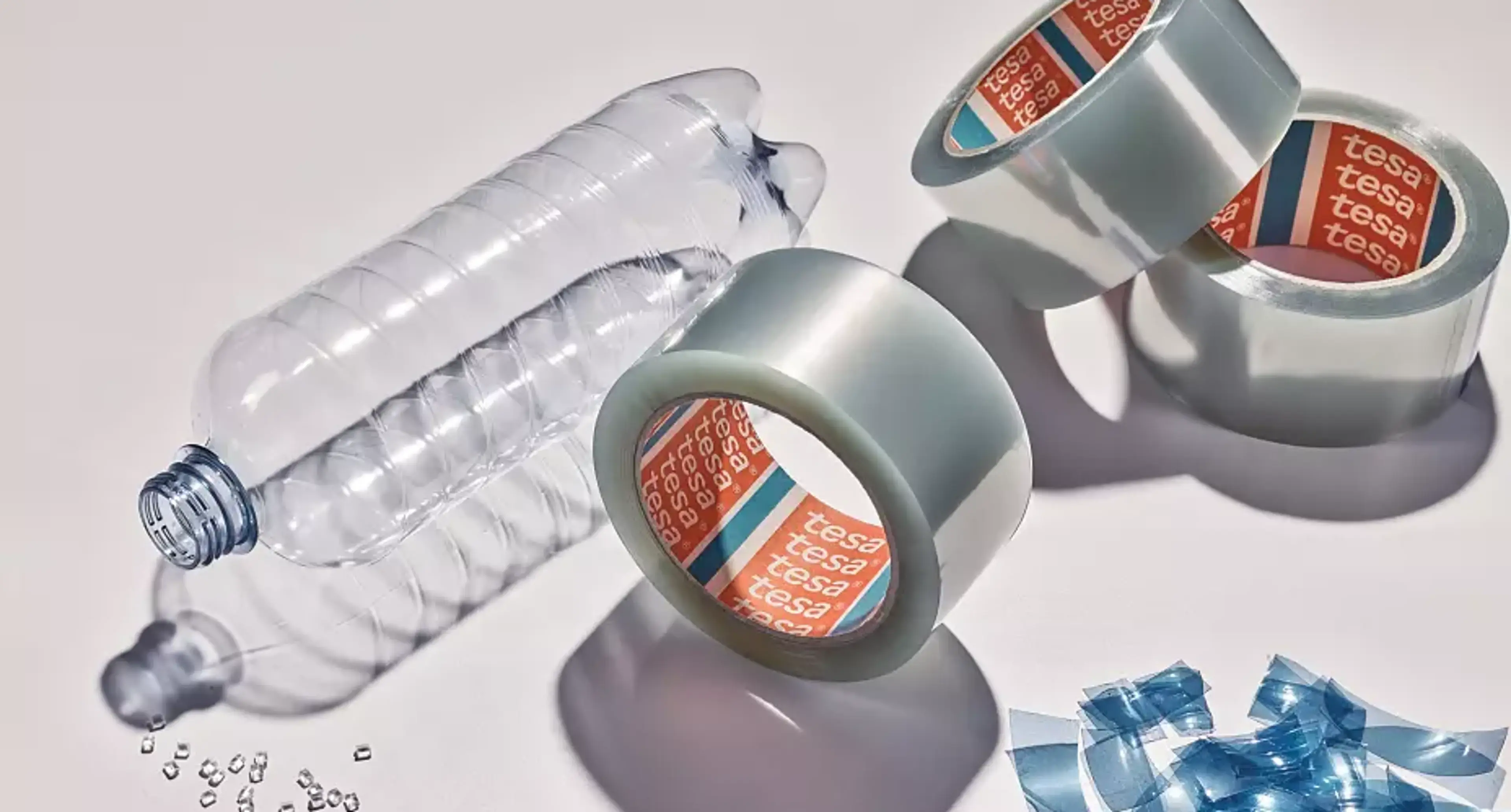 Tesa PCR-PET tape ved siden av tomflaske og PCR-PET pellets