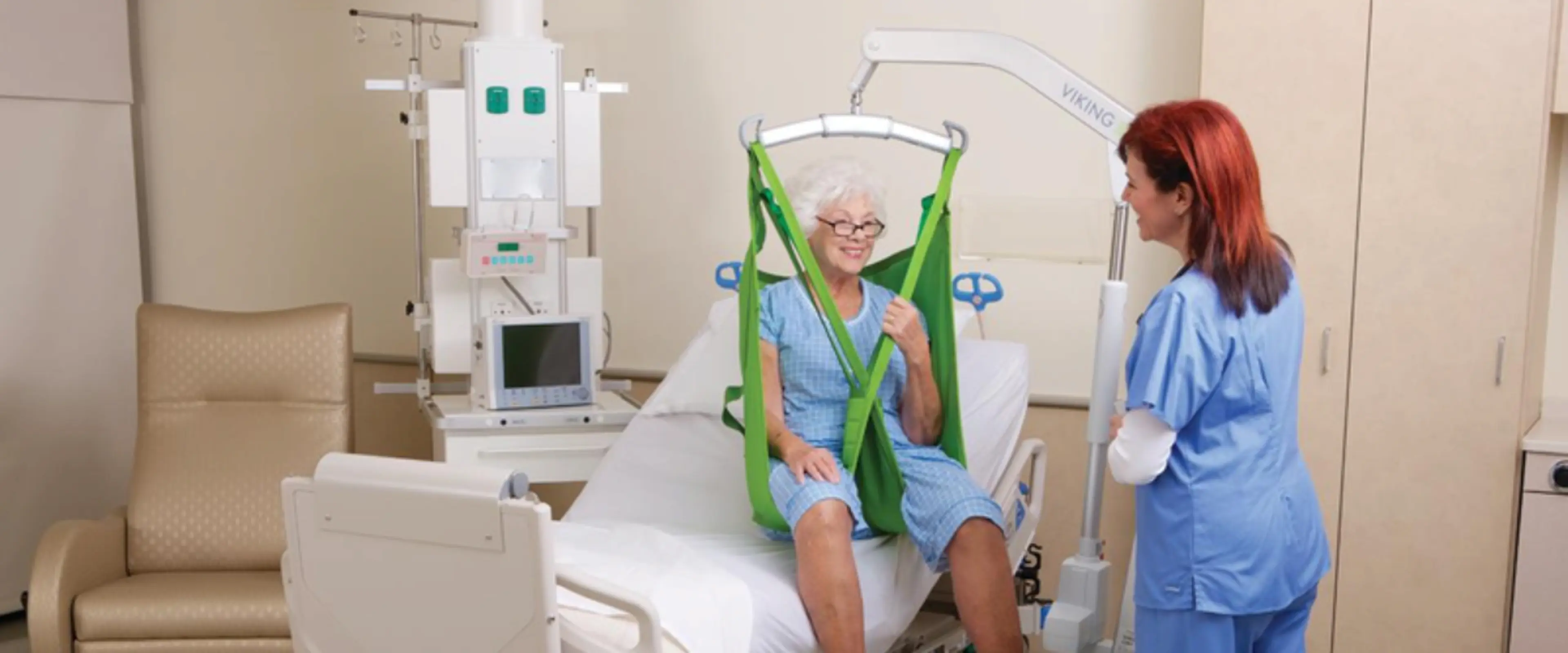 Pasient som sitter i en pasientløfter med sykepleier ved siden av