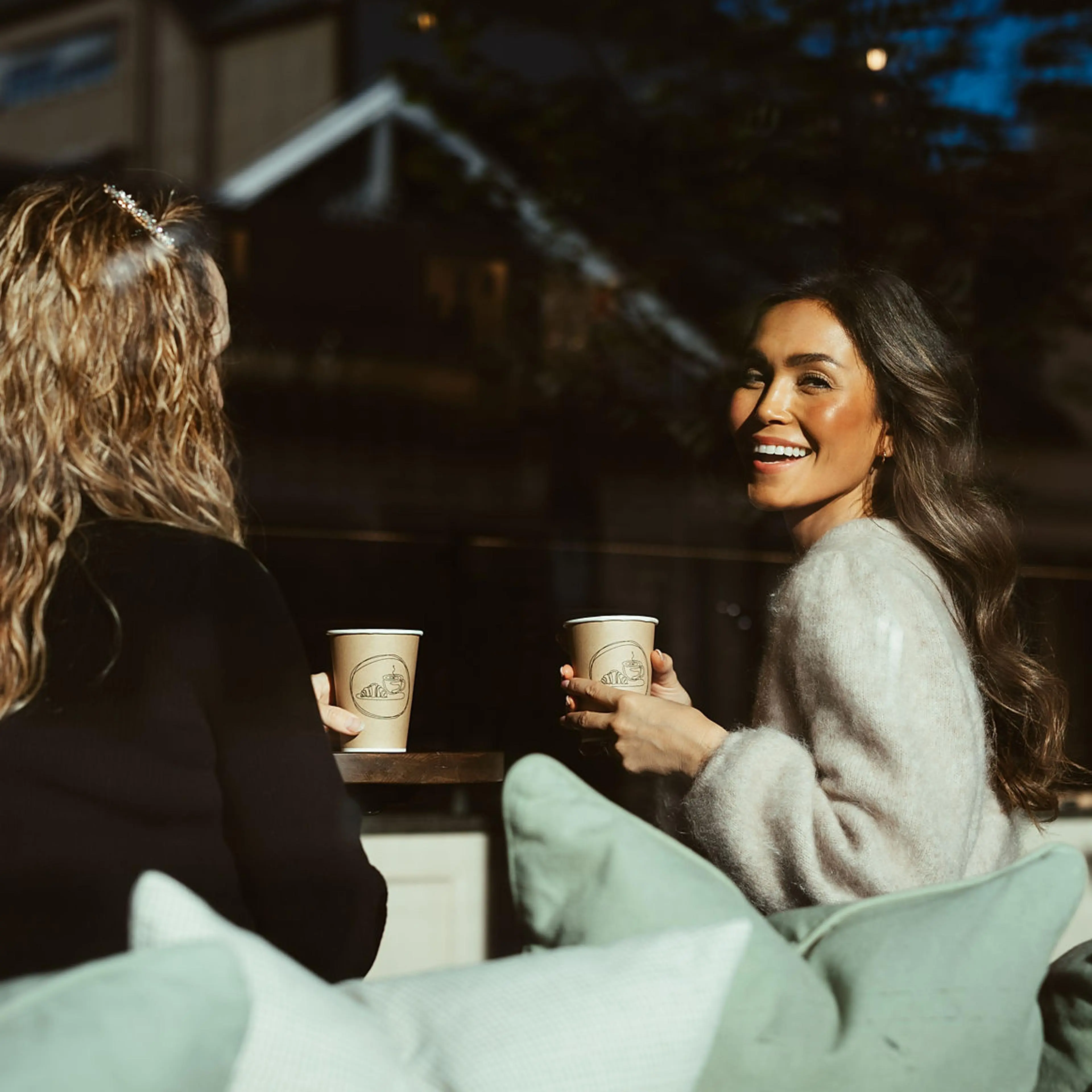 Kvinner på kafe drikker kaffe av stund engangskopper